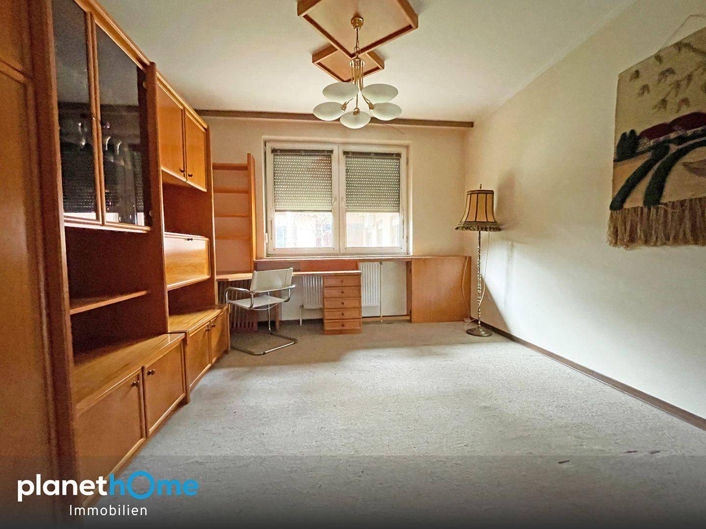 Ein Zimmer mit Teppichboden, Fenster mit Rollläden und praktischen Holzschränken.