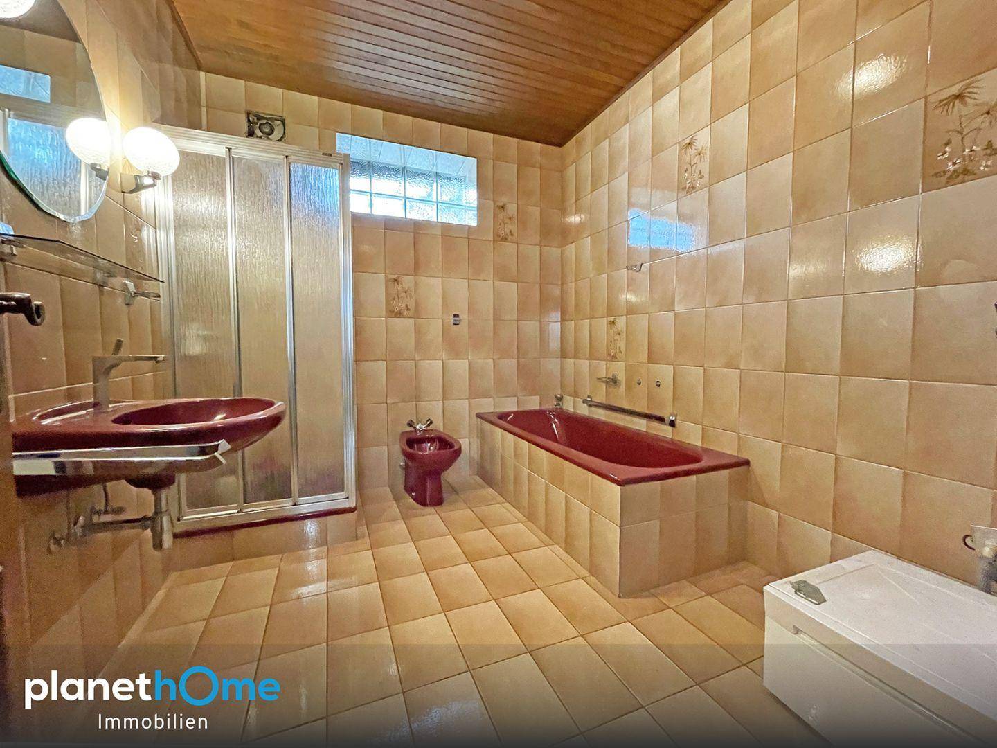 Badezimmer im Stil der 80er Jahre mit Fliesen, Dusche, Badewanne und Bidet in Terrakotta-Farben.