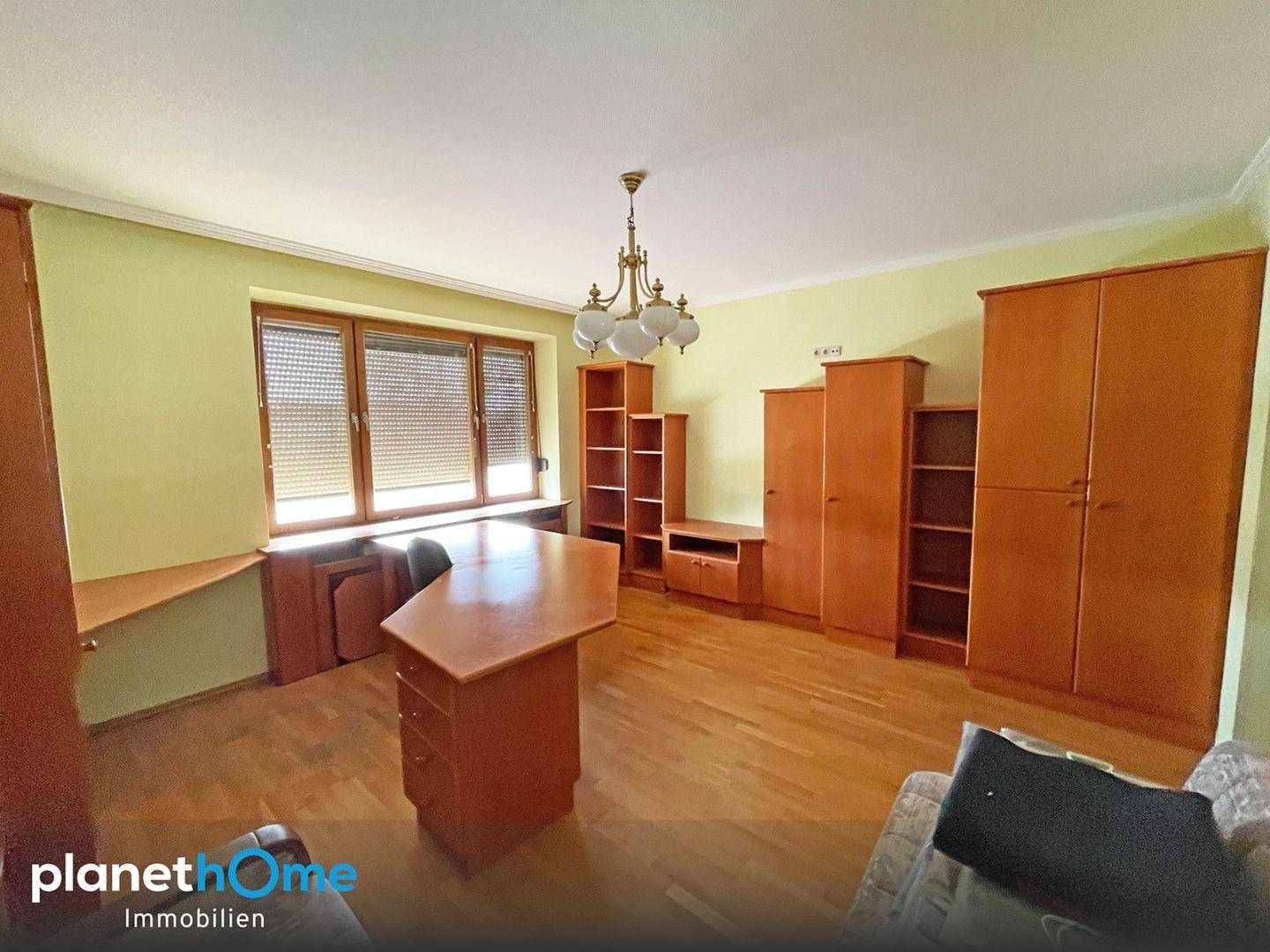 Helles Zimmer mit Holzboden, großem Fenster und viel Stauraum durch Holzschränke.