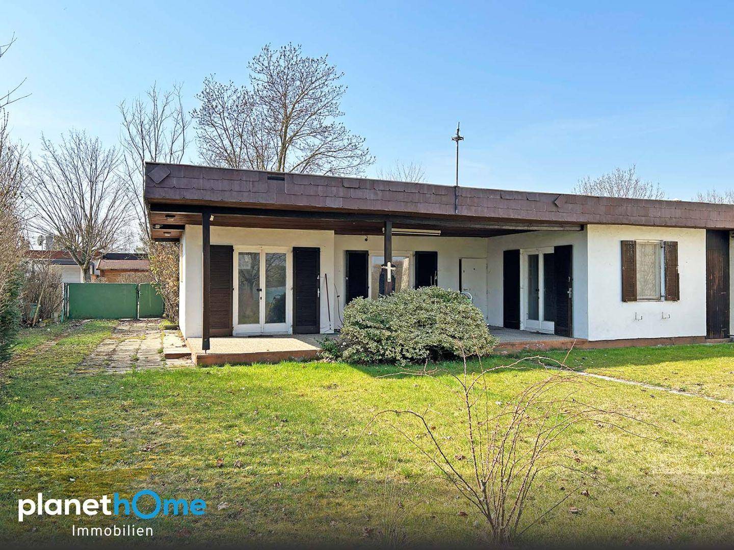 Einstöckiges Haus mit überdachter Terrasse und großem Gartenbereich, umgeben von Natur.