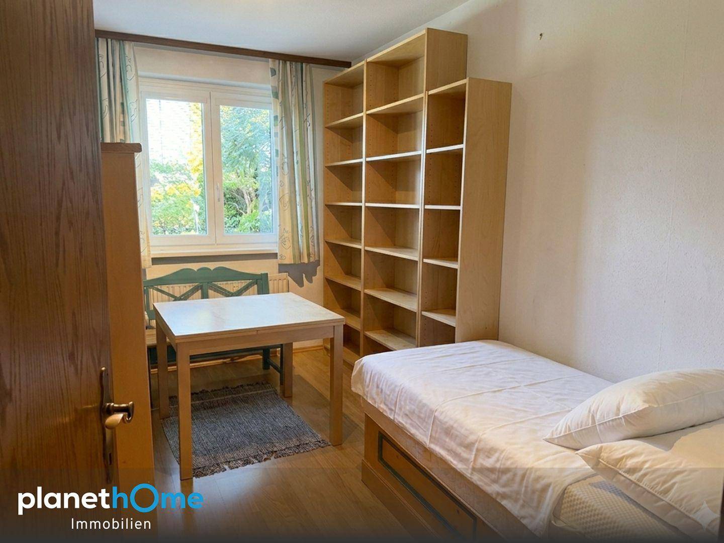 Kinder- oder Gästezimmer mit Einzelbett, Schreibtisch und großem Bücherregal.