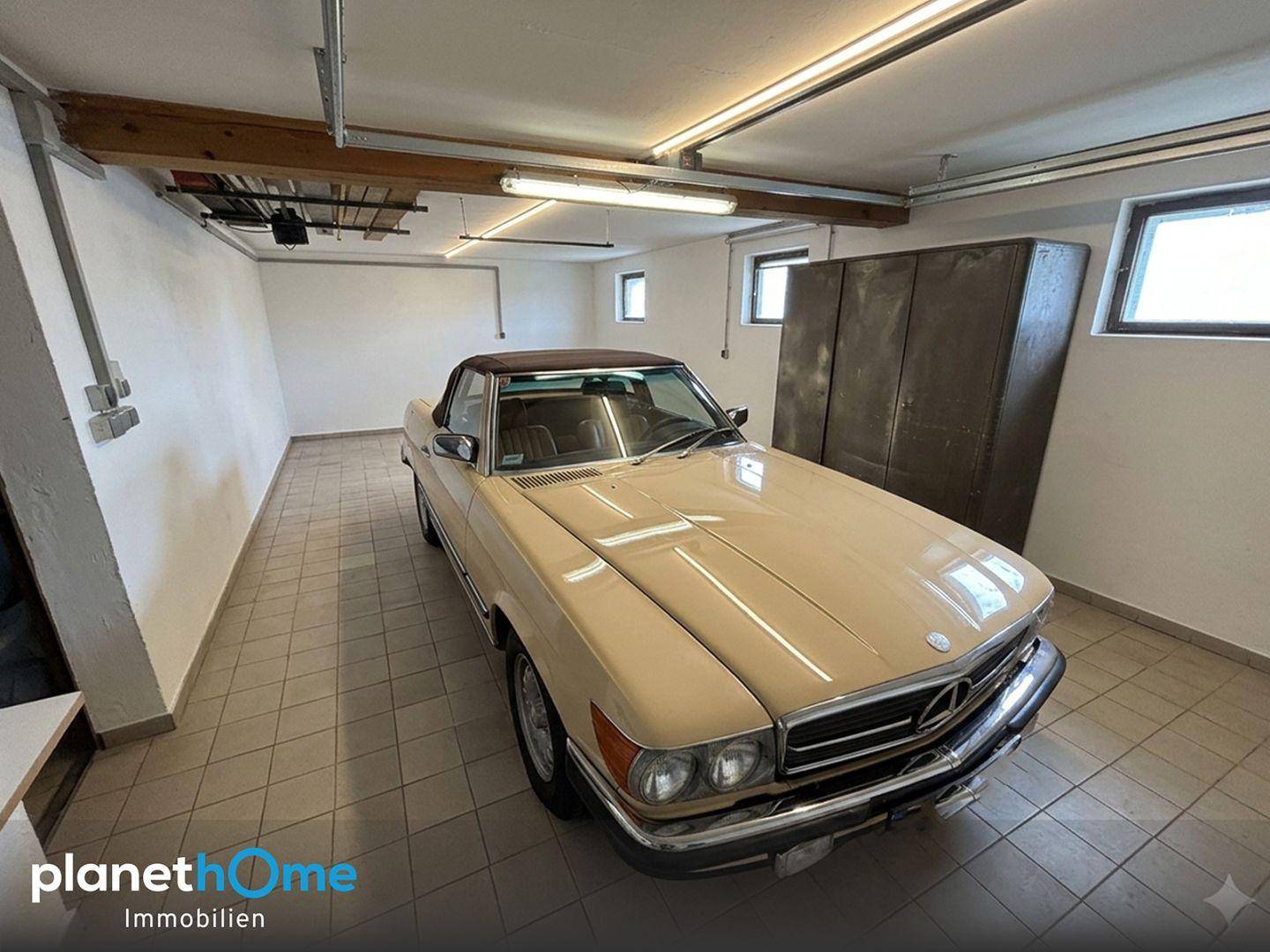 Geräumige Garage mit Fliesenboden, Fenstern und Platz für ein Fahrzeug.