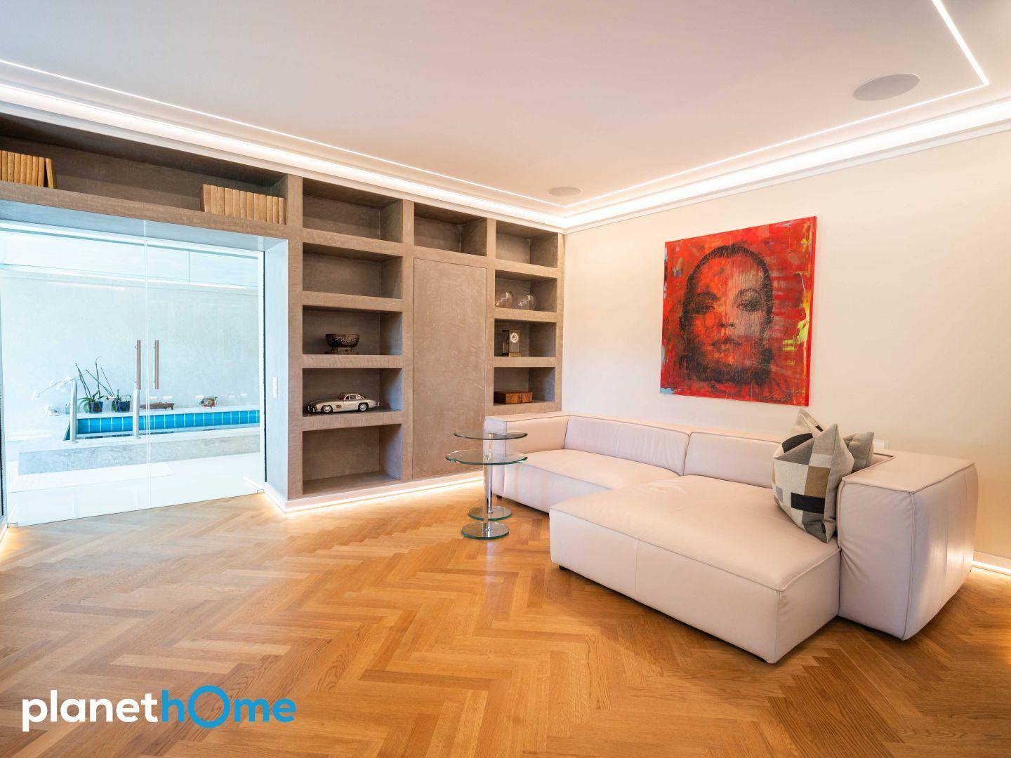 Stilvolles Wohnzimmer mit beigem Sofa, Kunstwerk und Blick auf den Innenpool.