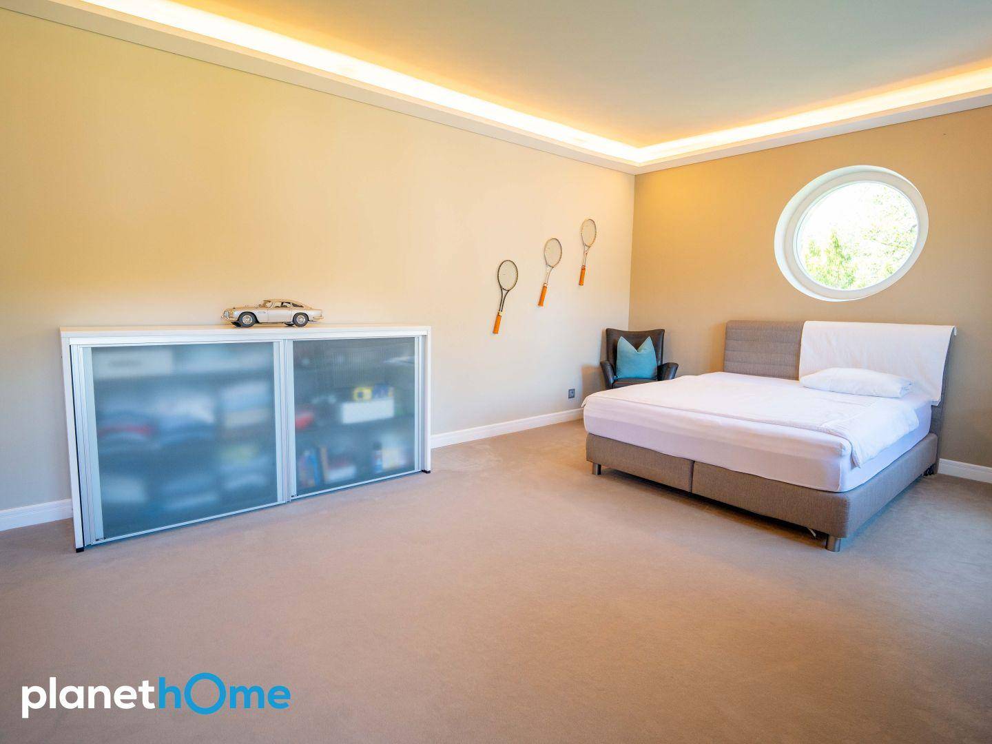 Helles Schlafzimmer mit Doppelbett, Teppichboden und runden Fenstern.
