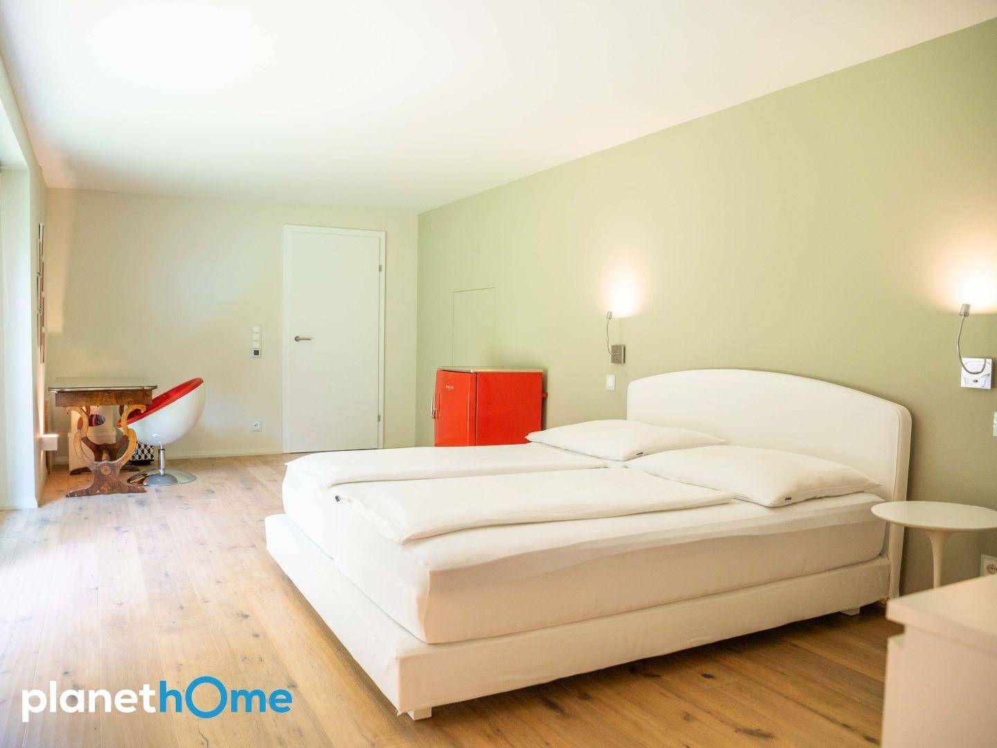 Helles Schlafzimmer mit Holzboden, Doppelbett und Zugang zum Garten.
