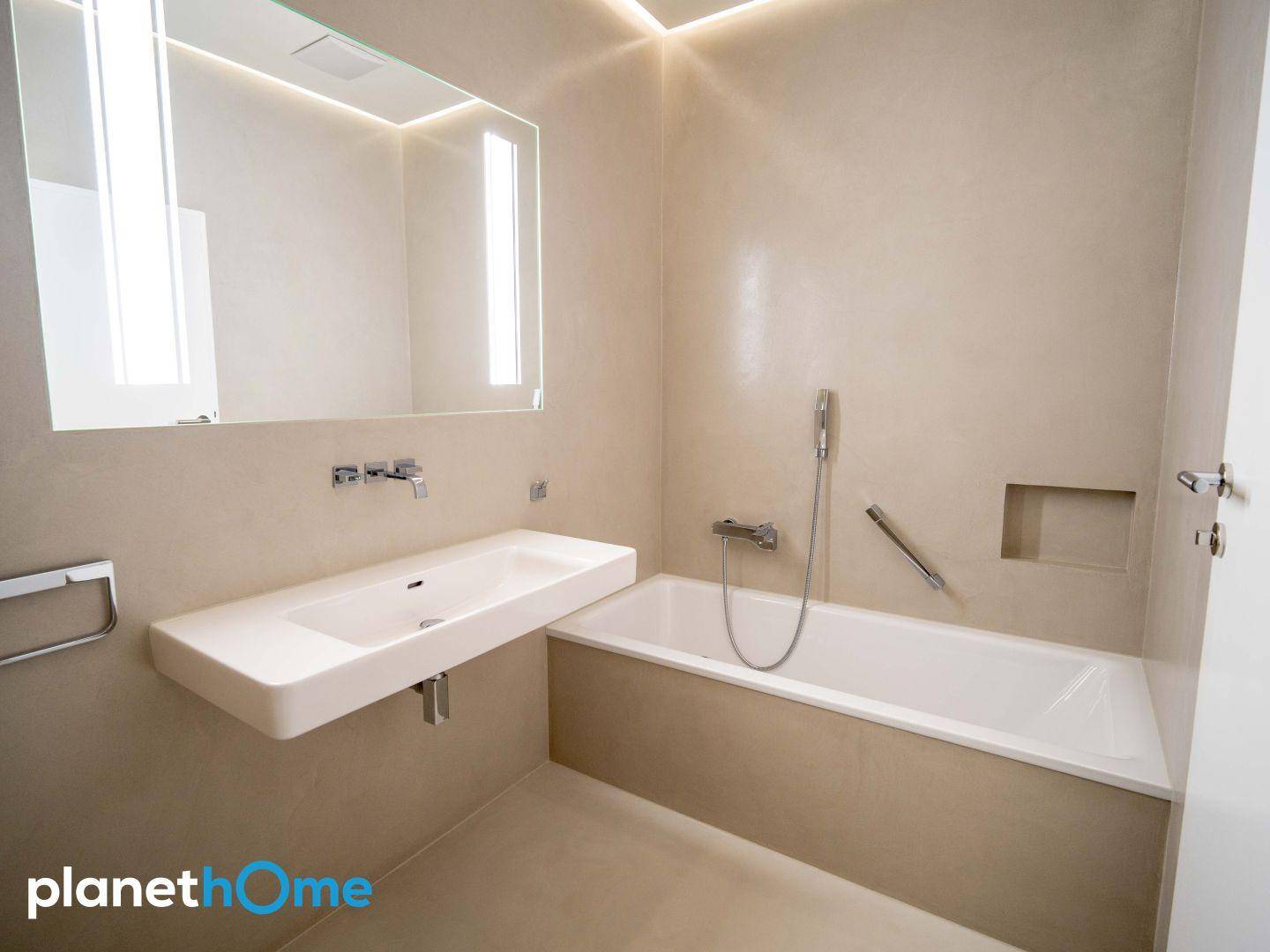 Modernes Badezimmer mit Badewanne, schwebendem Waschbecken und indirekter Beleuchtung.
