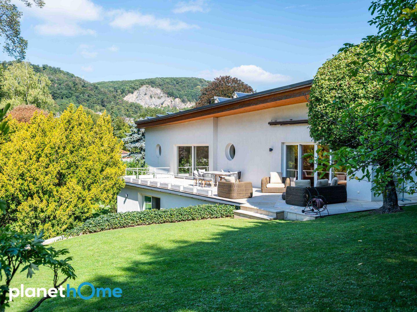 Moderne Hausfassade mit Terrasse, Garten und Blick auf die umliegende Natur.