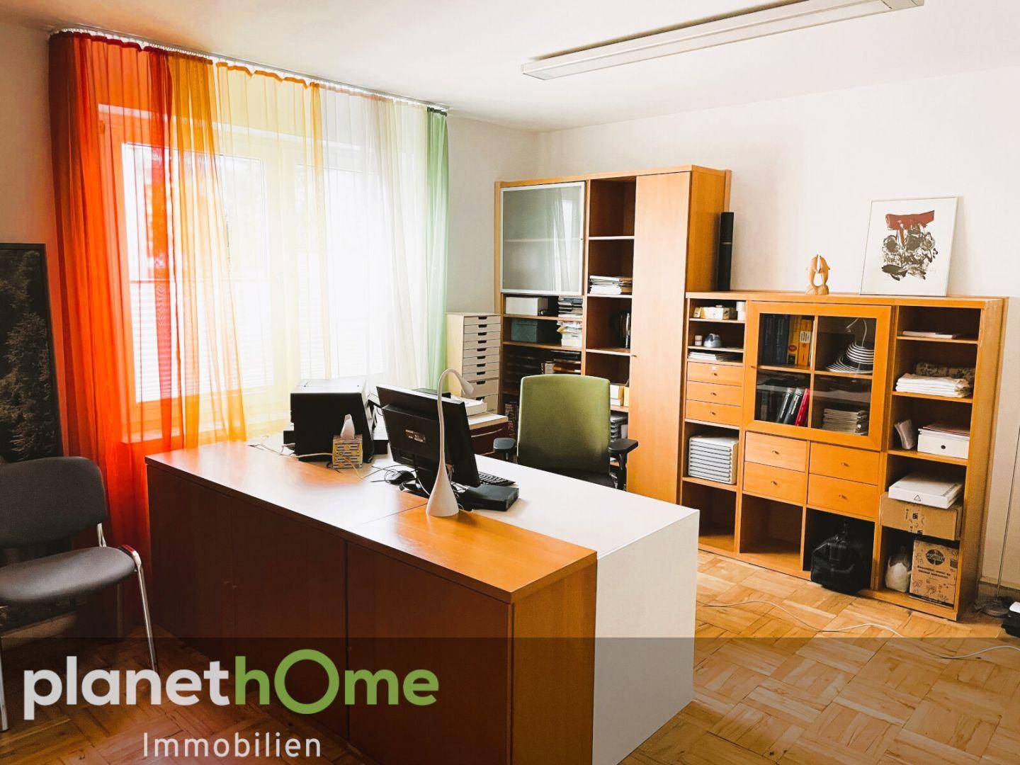 Helles Büro mit Holzregalen, Schreibtischen und farbenfrohen Vorhängen.