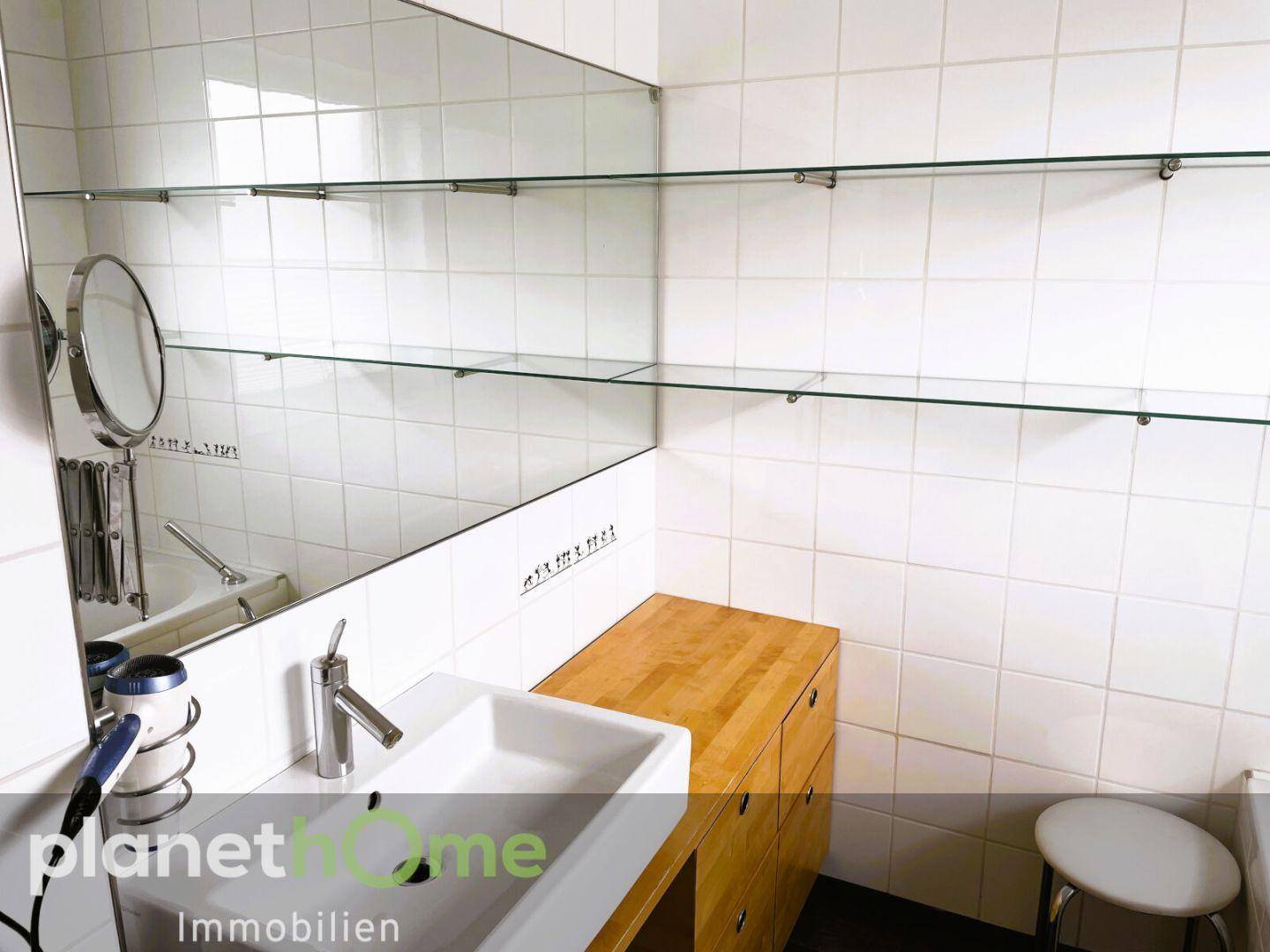 Helles Badezimmer mit modernem Waschbecken, Holzunterschrank und großem Spiegel.