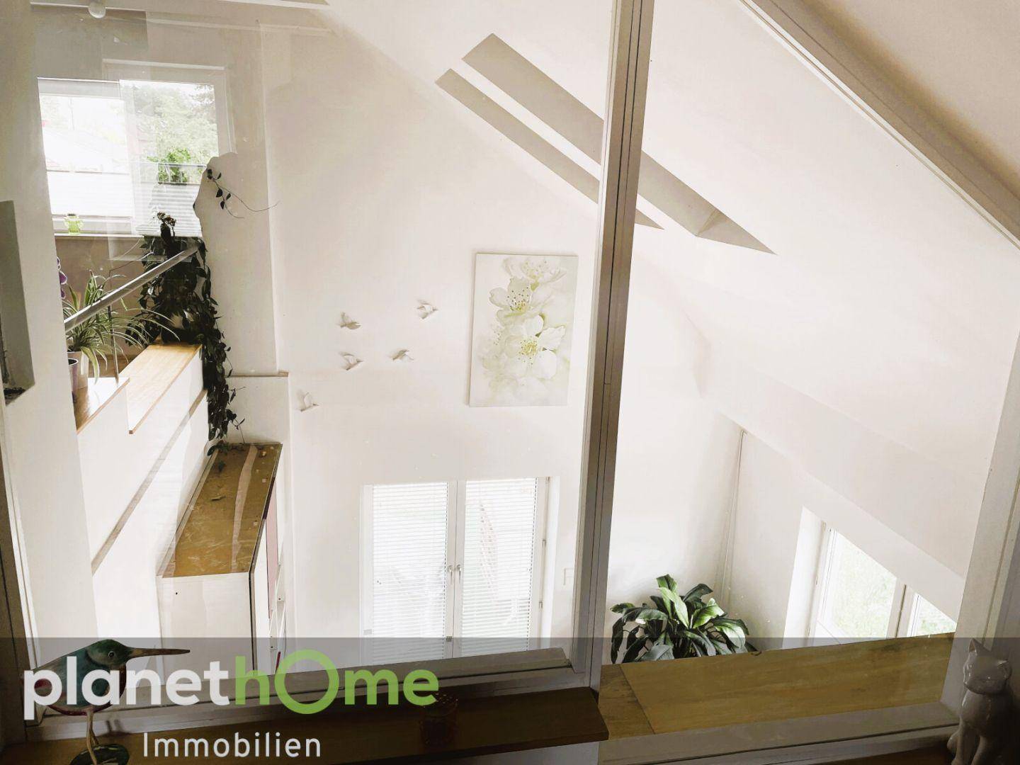 Helle Galerie im Obergeschoss mit Blick in den Wohnbereich und großen Fenstern.