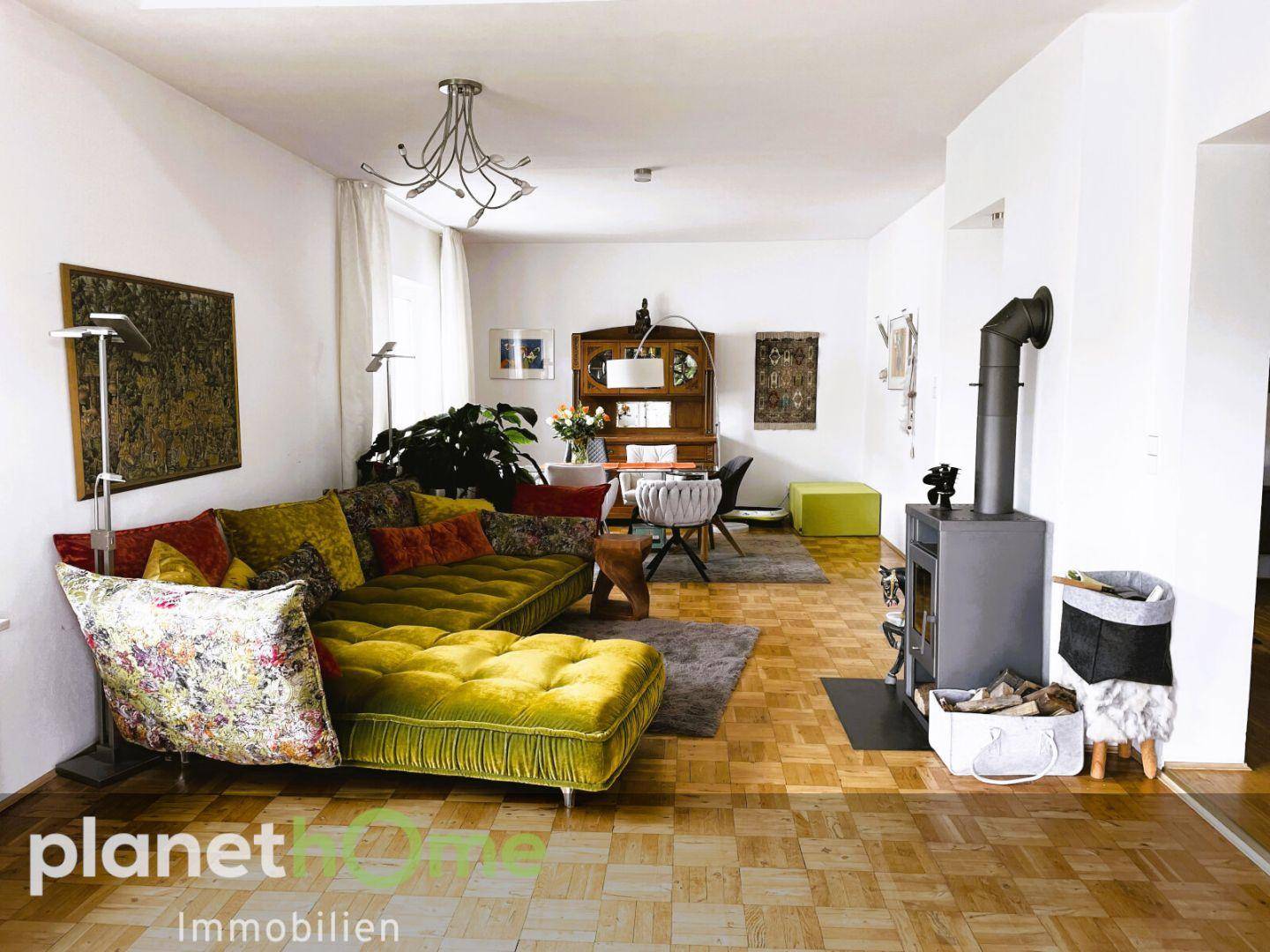 Geräumiges Wohnzimmer mit Parkettboden, gemütlichem Kaminofen und farbenfrohem Sofa.