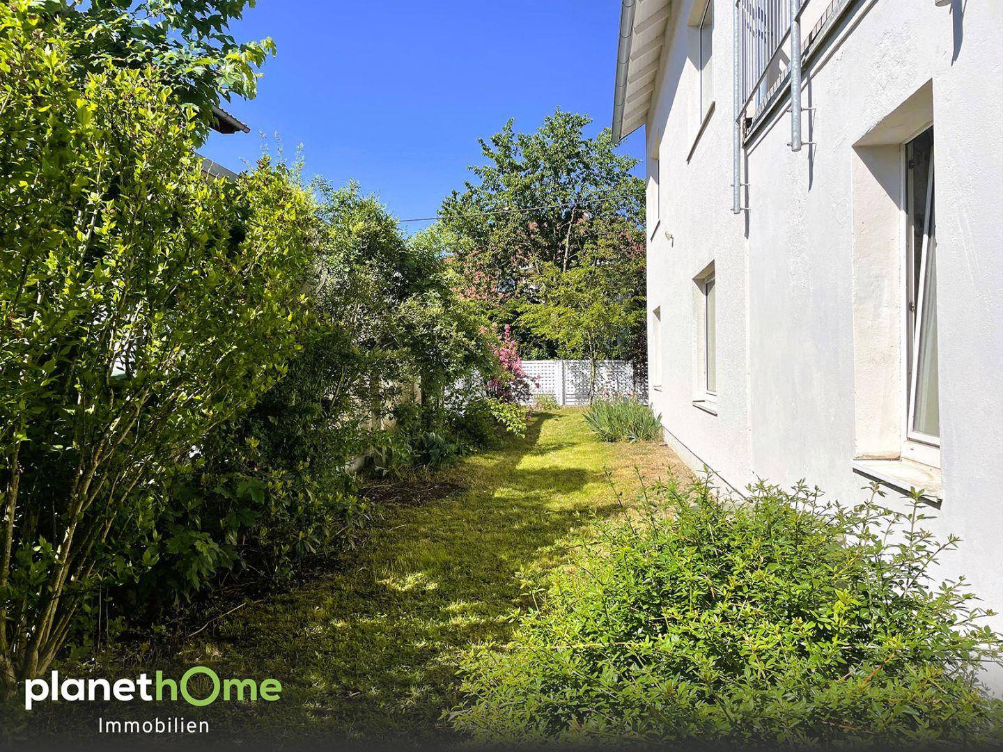 Gepflegter Gartenbereich entlang des Hauses mit viel Grün und Sträuchern.