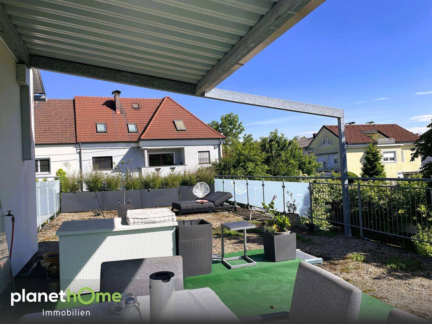 Große Sonnenterrasse mit Sitzgelegenheiten und Blick auf die umliegenden Häuser.