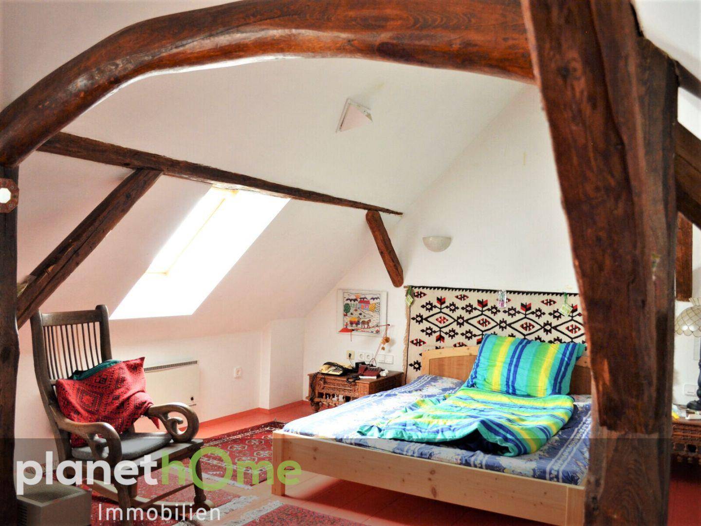 Gemütliches Schlafzimmer im Dachgeschoss mit Holzbalken und Dachfenster.