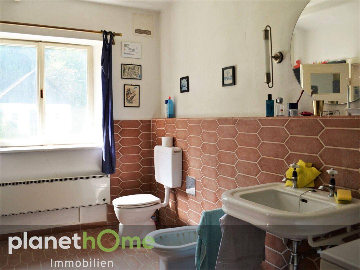 Badezimmer mit WC, Bidet und Waschbecken, gefliest in warmen Erdtönen.