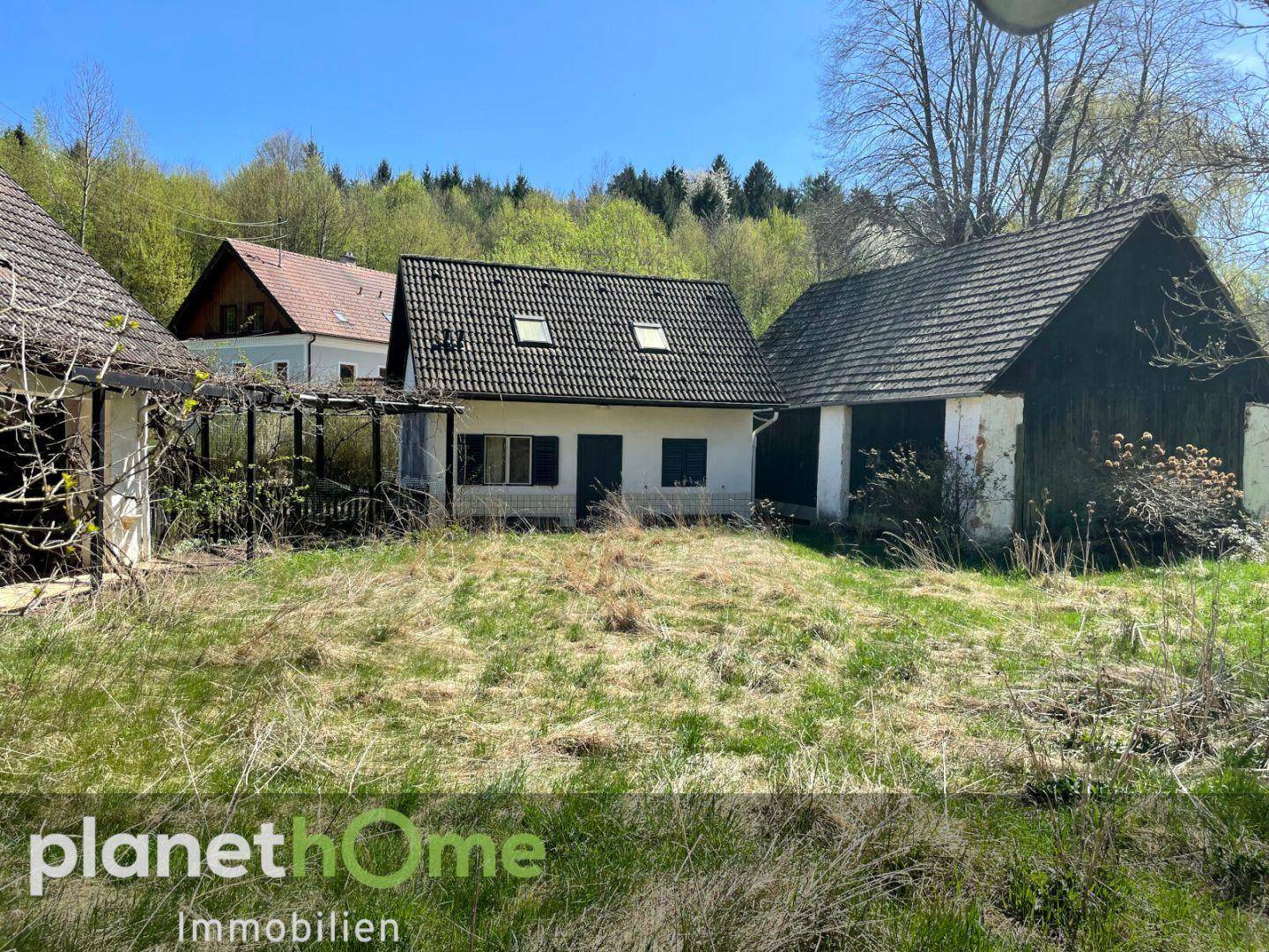 Ländliches Anwesen mit Haupthaus und Nebengebäude umgeben von Natur.