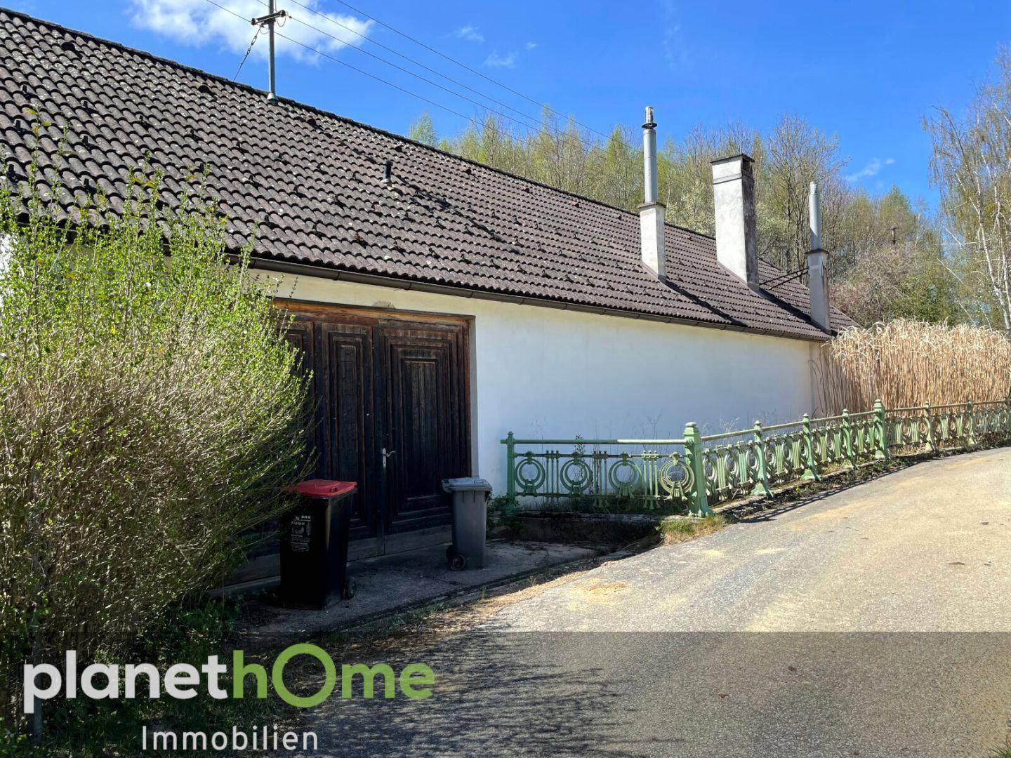 Garage mit Holztoren und Zufahrt, Teil des ländlichen Anwesens.