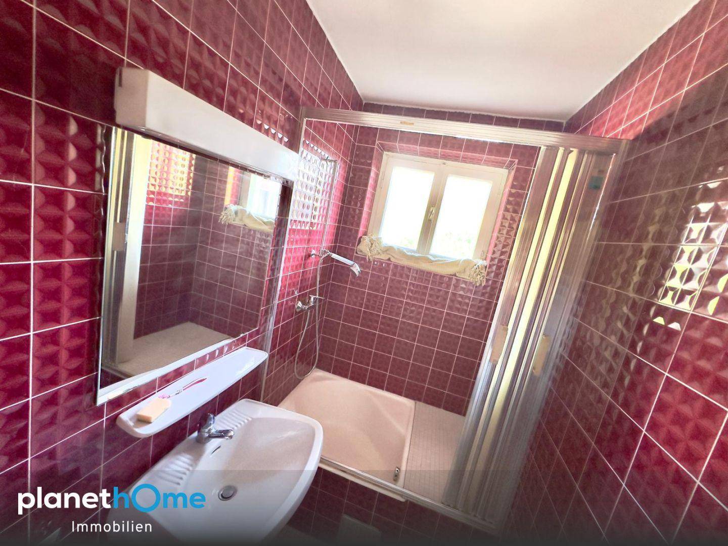 Badezimmer mit roten Fliesen, Duschkabine, Bidet und Fenster für Tageslicht.