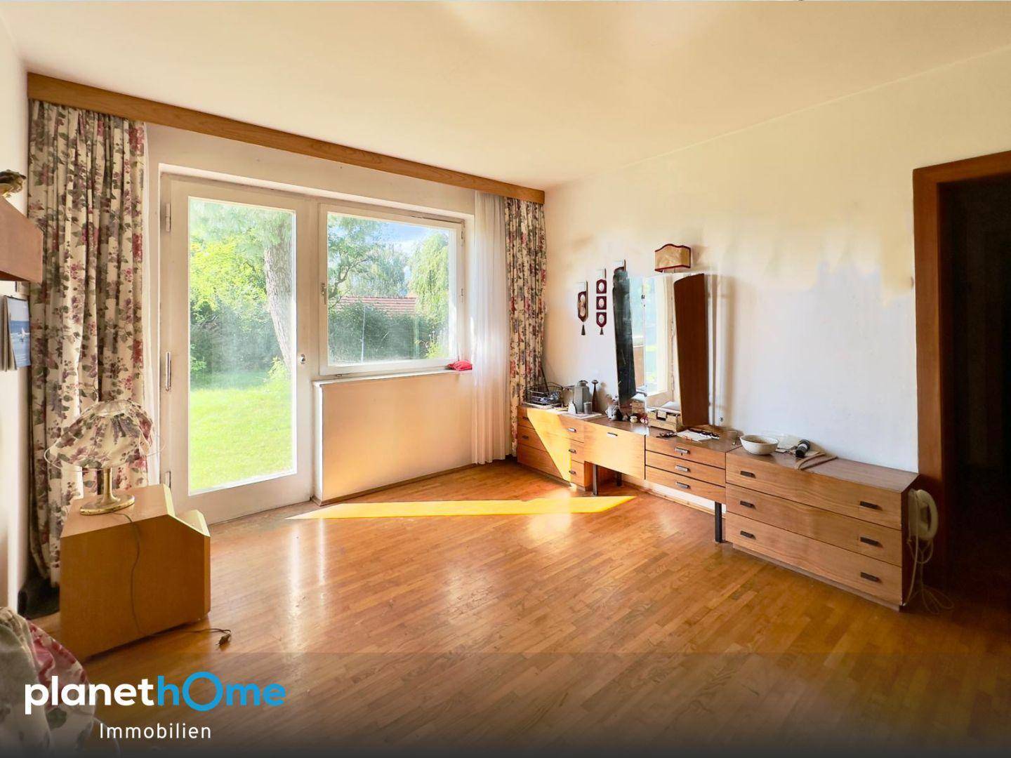 Helles Wohnzimmer mit Parkettboden, großen Fenstern und direktem Zugang zum Garten.