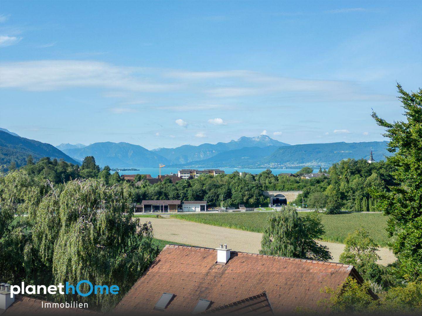 Weitläufiger Panoramablick auf einen See und die umliegende Berglandschaft.