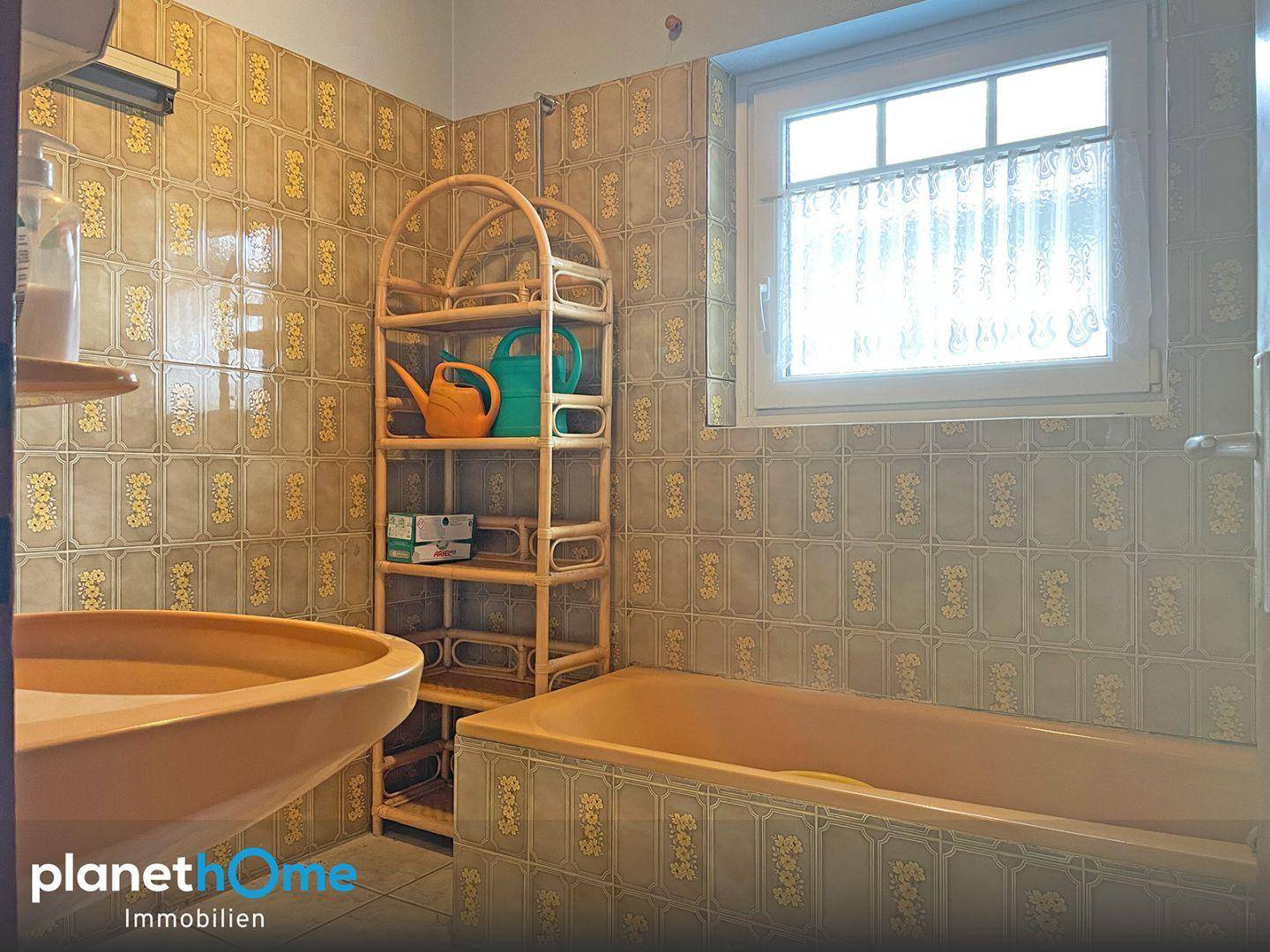 Badezimmer mit Badewanne, Waschbecken und Fenster in traditionellem Stil.
