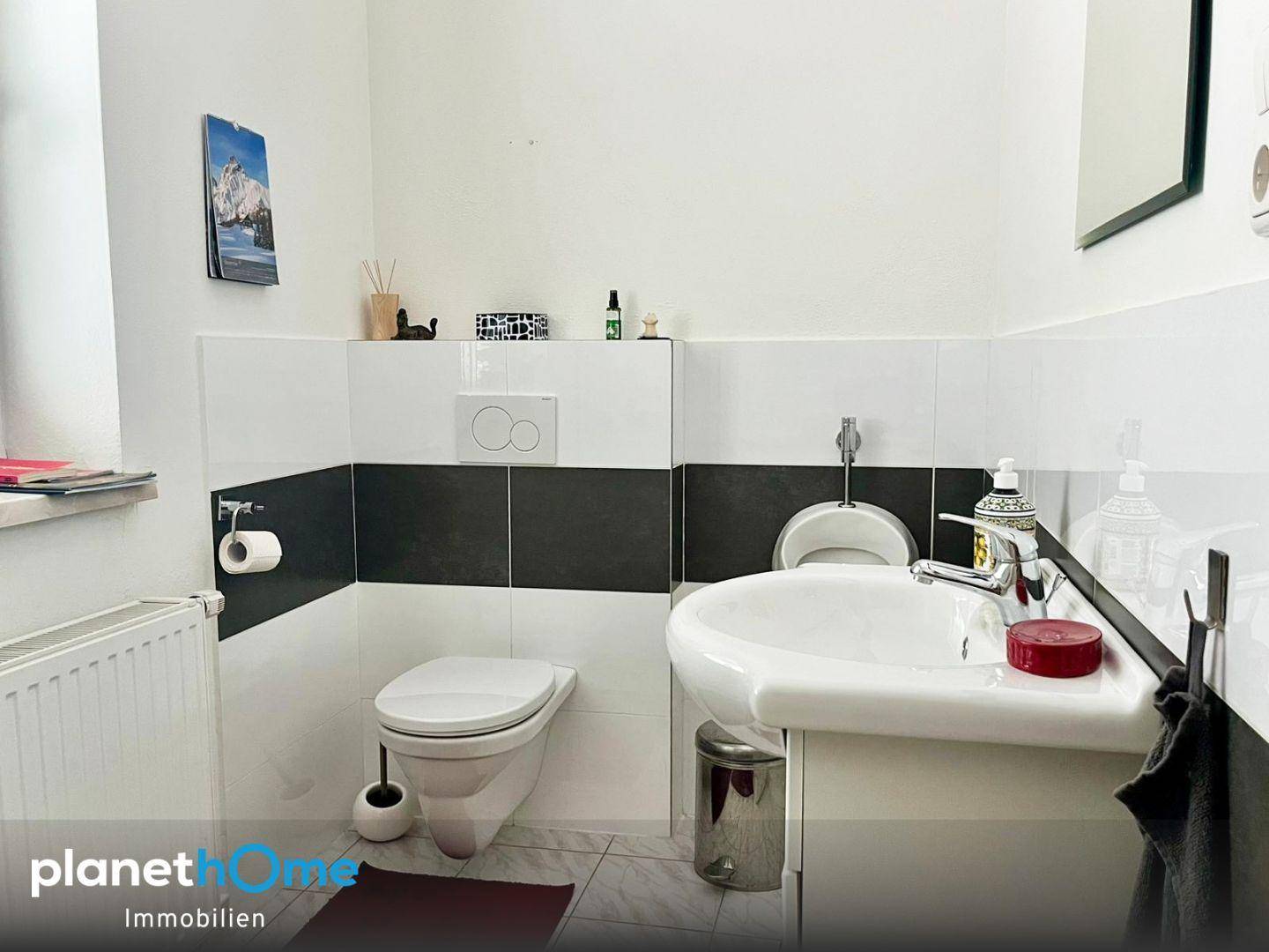 Kleines Gäste-WC mit Wand-WC, Waschbecken und Bidet in Schwarz-Weiß-Fliesen.