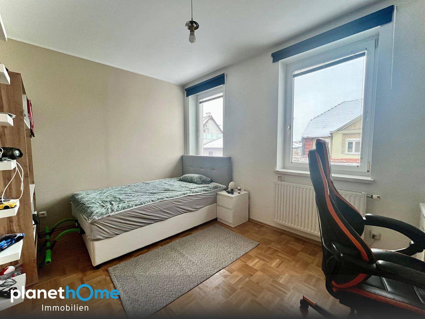 Schlafzimmer mit Einzelbett, Nachttisch und ergonomischem Schreibtischstuhl.