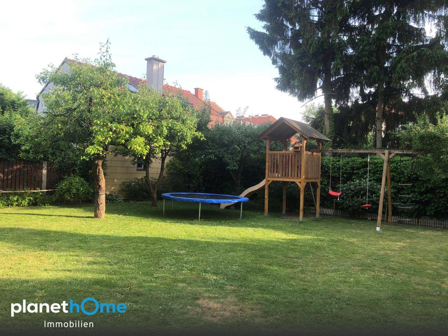 Großer, grüner Garten mit Spielgeräten wie Trampolin und Schaukel.