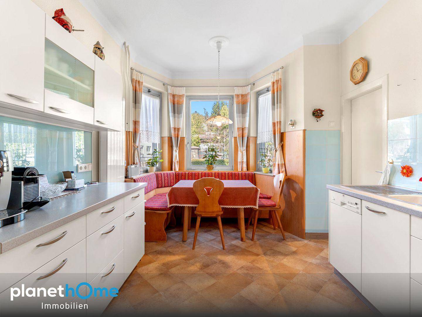 Helle Küche mit Einbauküche, Essbereich und Fensterfront mit Blick in den Garten.