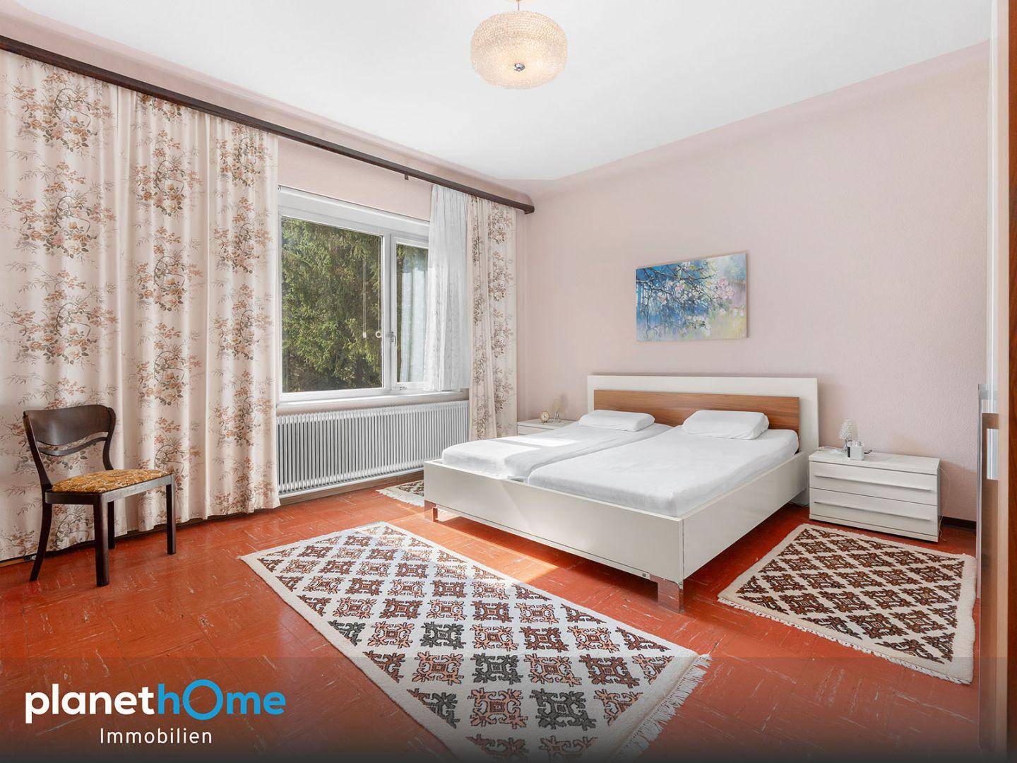 Schlafzimmer mit Doppelbett, Teppichen und Fenster mit Blick ins Grüne.