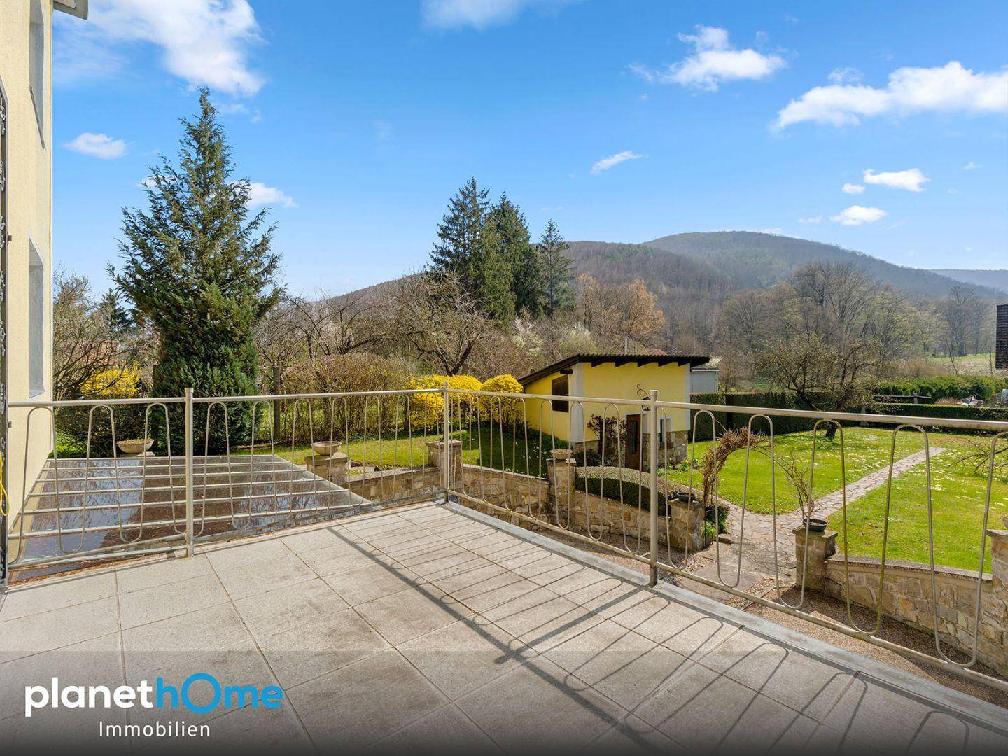Geräumiger Balkon mit Fliesenboden und Metallgeländer, bietet weiten Blick auf die Landschaft.