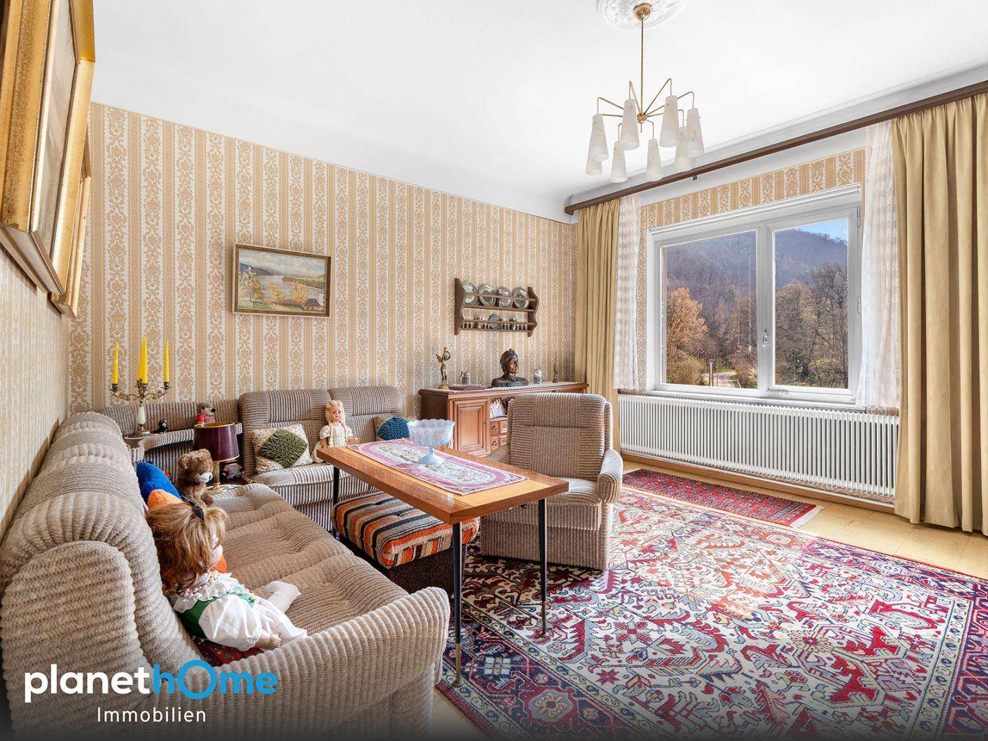Gemütliches Wohnzimmer mit Tapeten, Sofas und großem Fenster mit Blick auf die Natur.