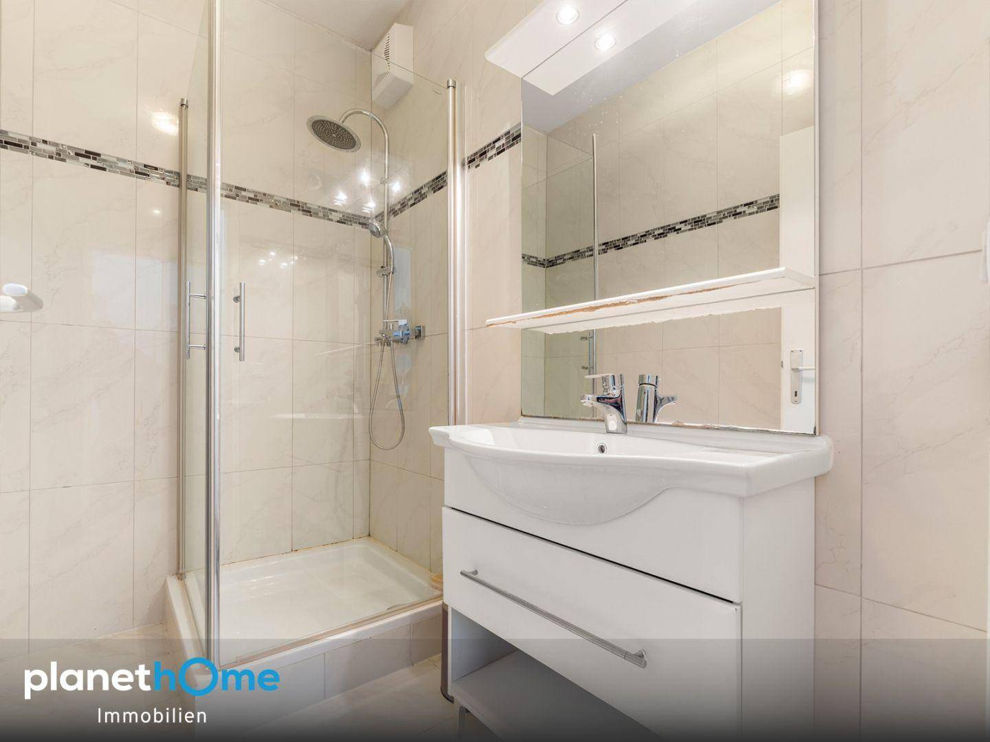 Badezimmer mit Duschkabine, Einzelwaschbecken und einem Spiegelschrank über dem Waschtisch.