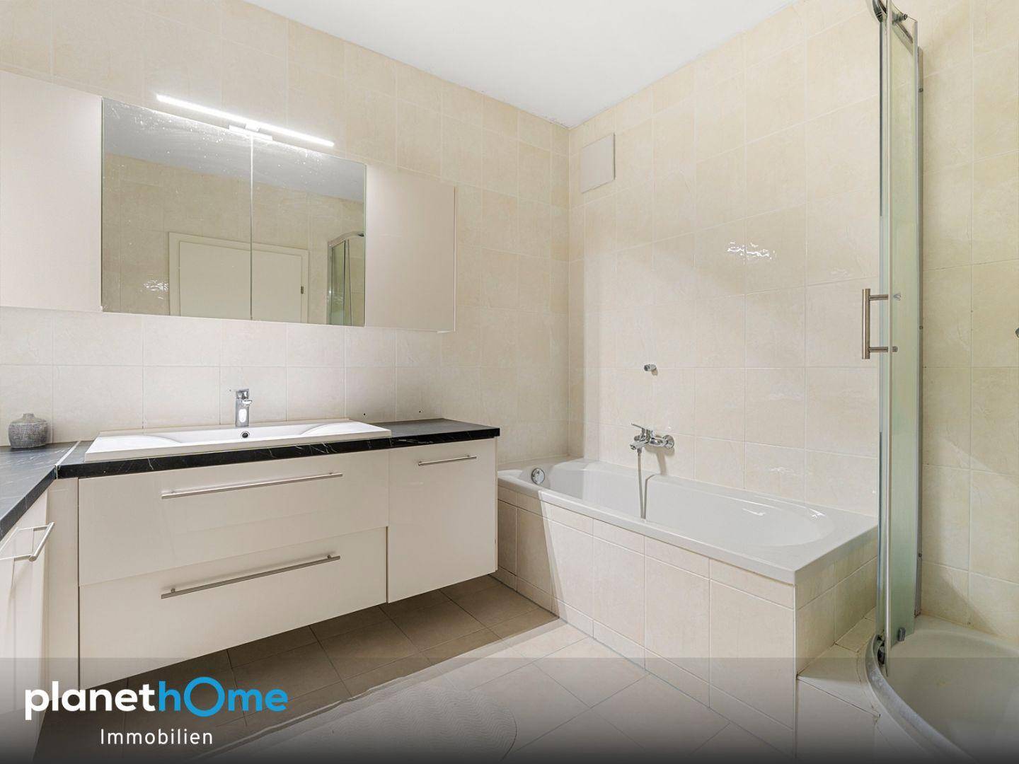 Badezimmer mit Badewanne, Duschkabine, Doppelwaschbecken und einem großen Spiegelschrank.