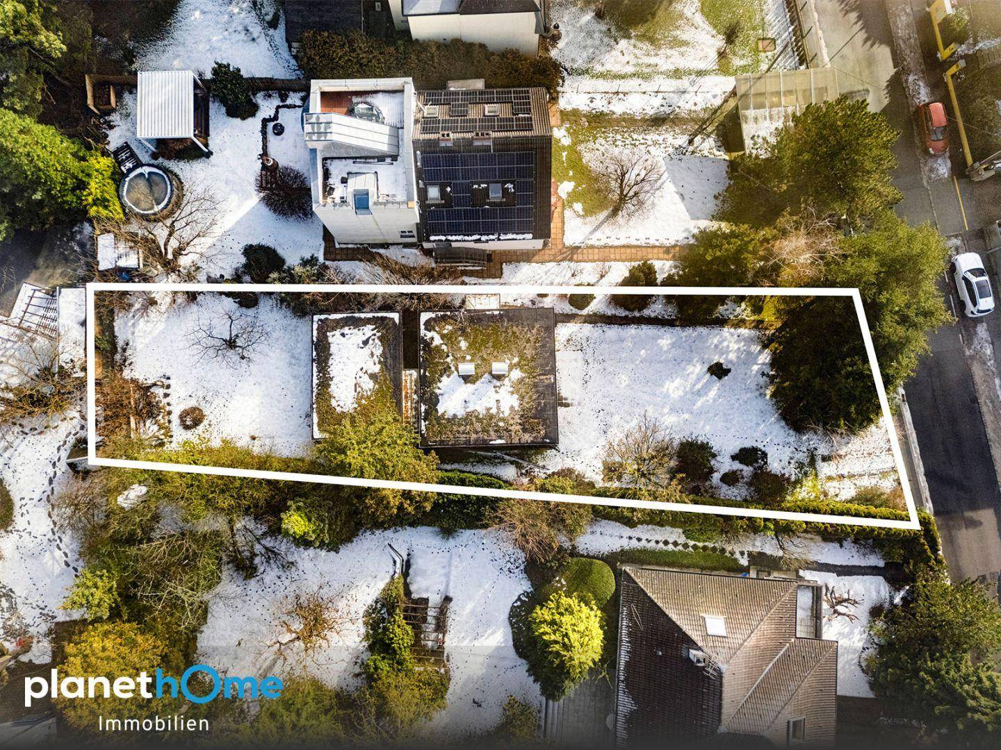 Luftaufnahme des Grundstücks im Winter mit Schnee, umgeben von Bäumen und Nachbargebäuden.