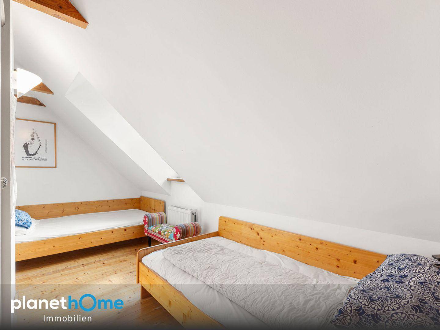 Gemütlicher Schlafbereich mit Holzbett, Holzboden und Dachschrägen.