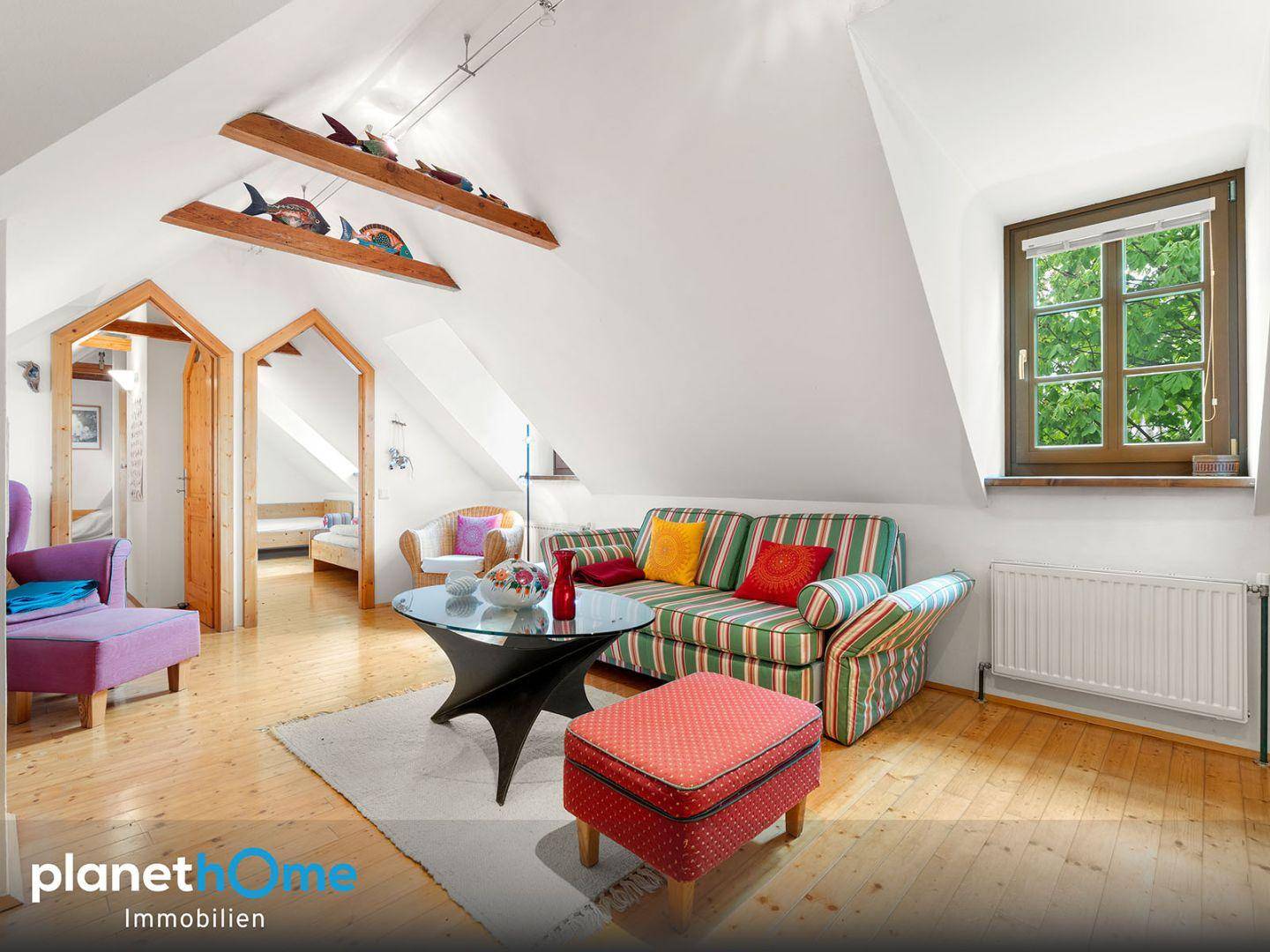 Helles Wohnzimmer mit gestreiftem Sofa, Holzboden und Dachschrägen.