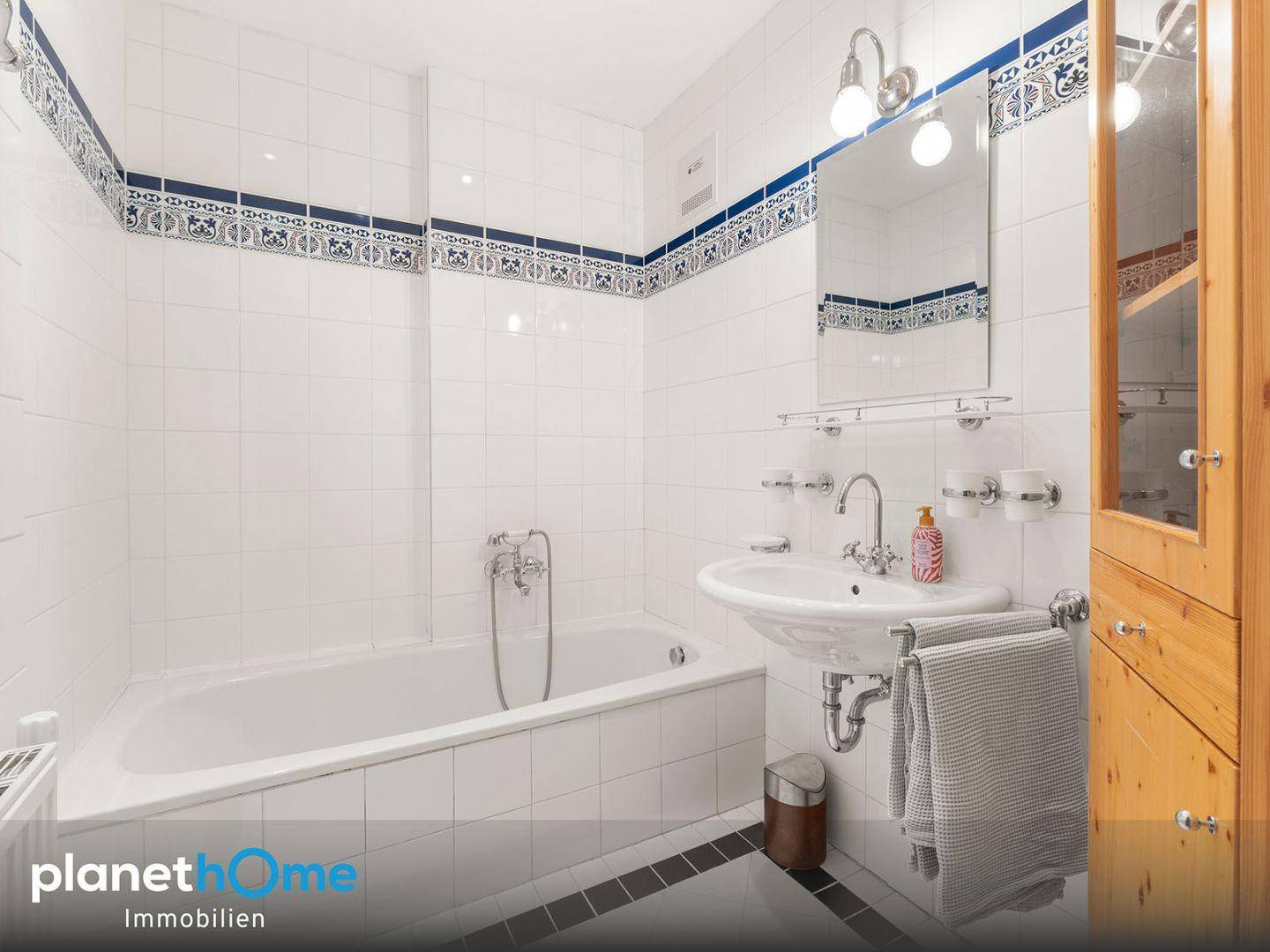 Gefliestes Badezimmer mit Badewanne, Waschbecken und traditionellen blauen Bordüren.
