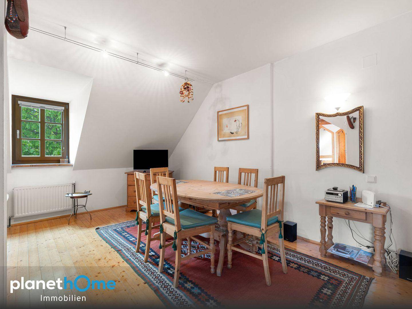 Gemütlicher Essbereich im Dachgeschoss mit Holztisch, Teppich und Fenster für natürliches Licht.