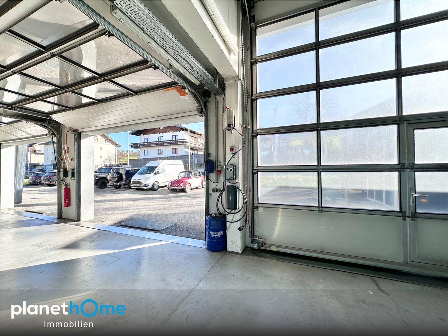 Innenansicht der Garage mit Blick nach draußen und einem klassischen Auto, viel Platz für Arbeiten.