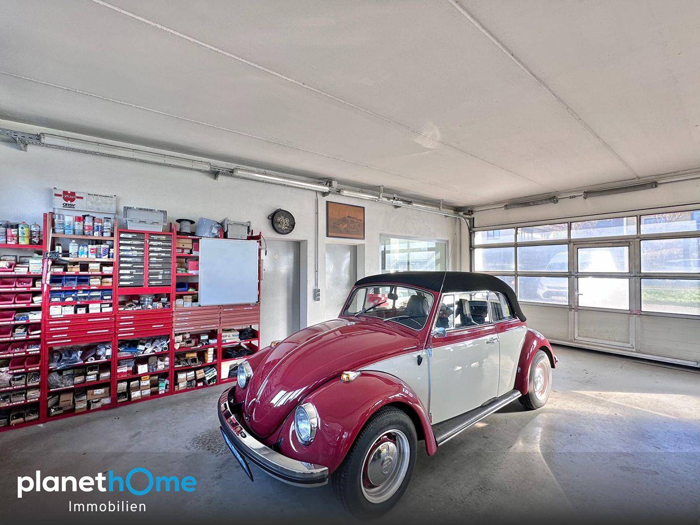 Geräumige Werkstatt mit einem Oldtimer, umfangreichen Regalen und viel Platz für Hobbys oder Arbeit.