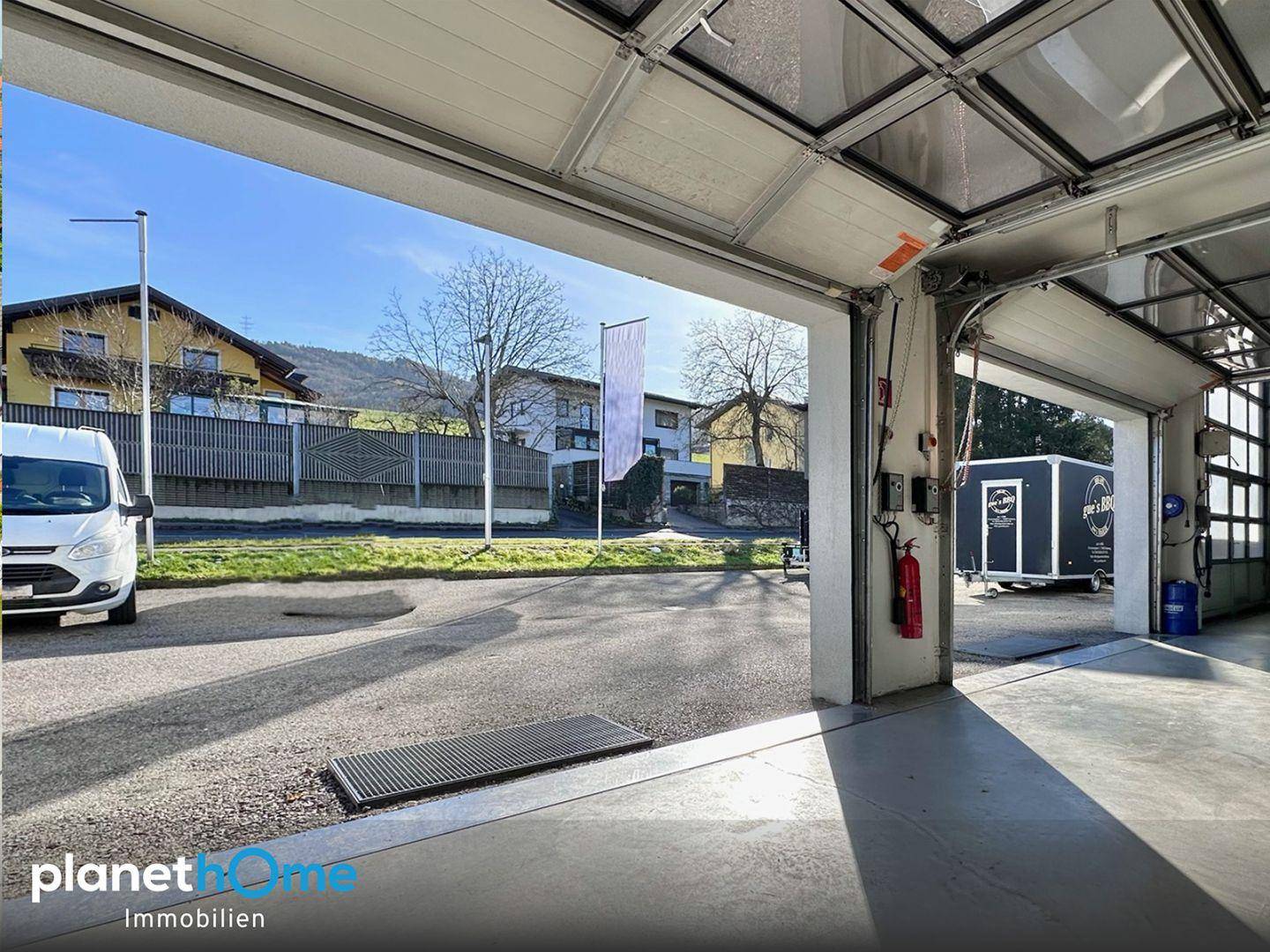 Heller Garagenbereich mit Blick auf die Straße und einen Anhänger, ausgestattet für verschiedene Tätigkeiten.