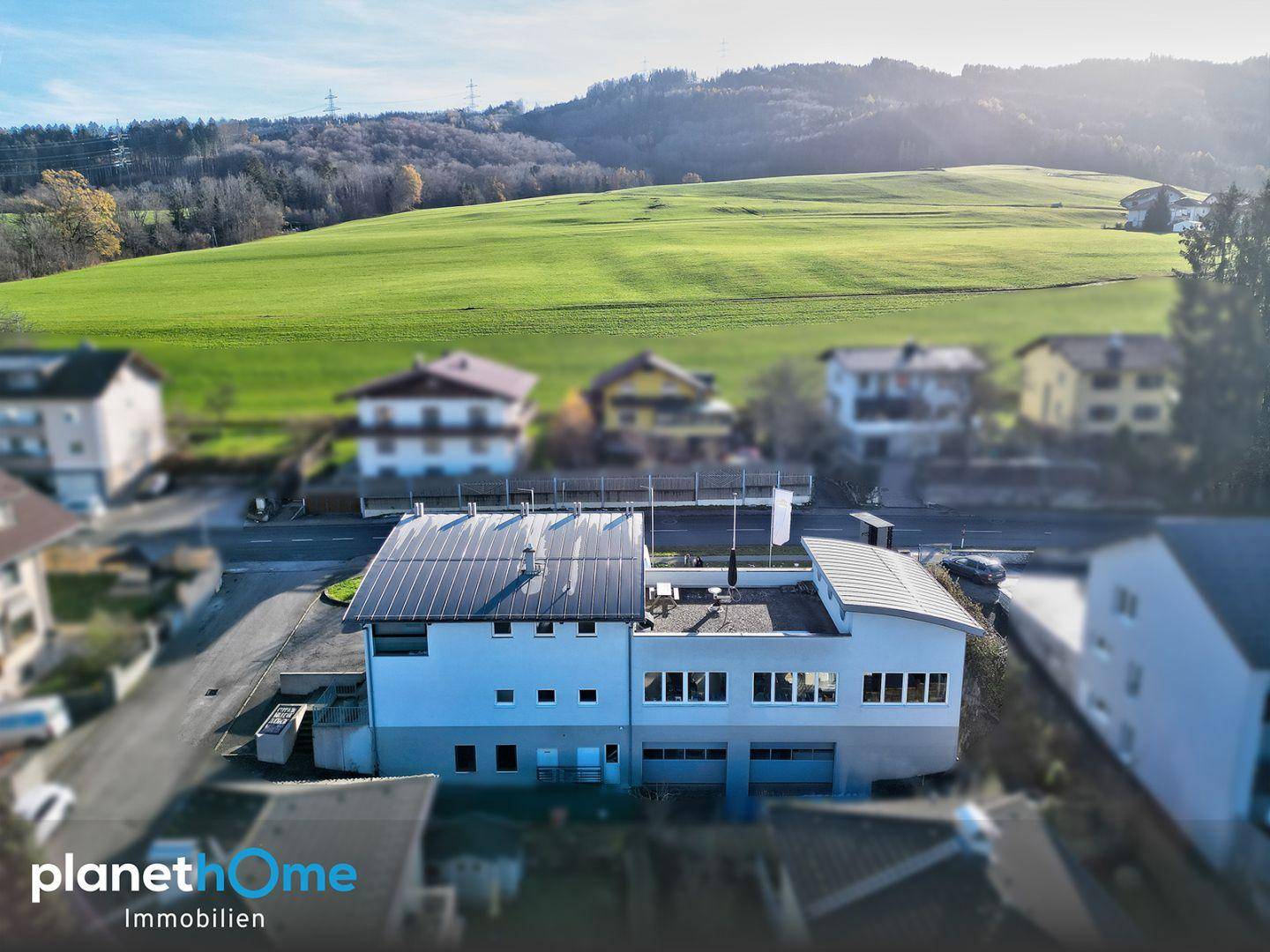 Rückansicht des Geschäftsgebäudes mit Blick auf grüne Hügel und die weite Landschaft.