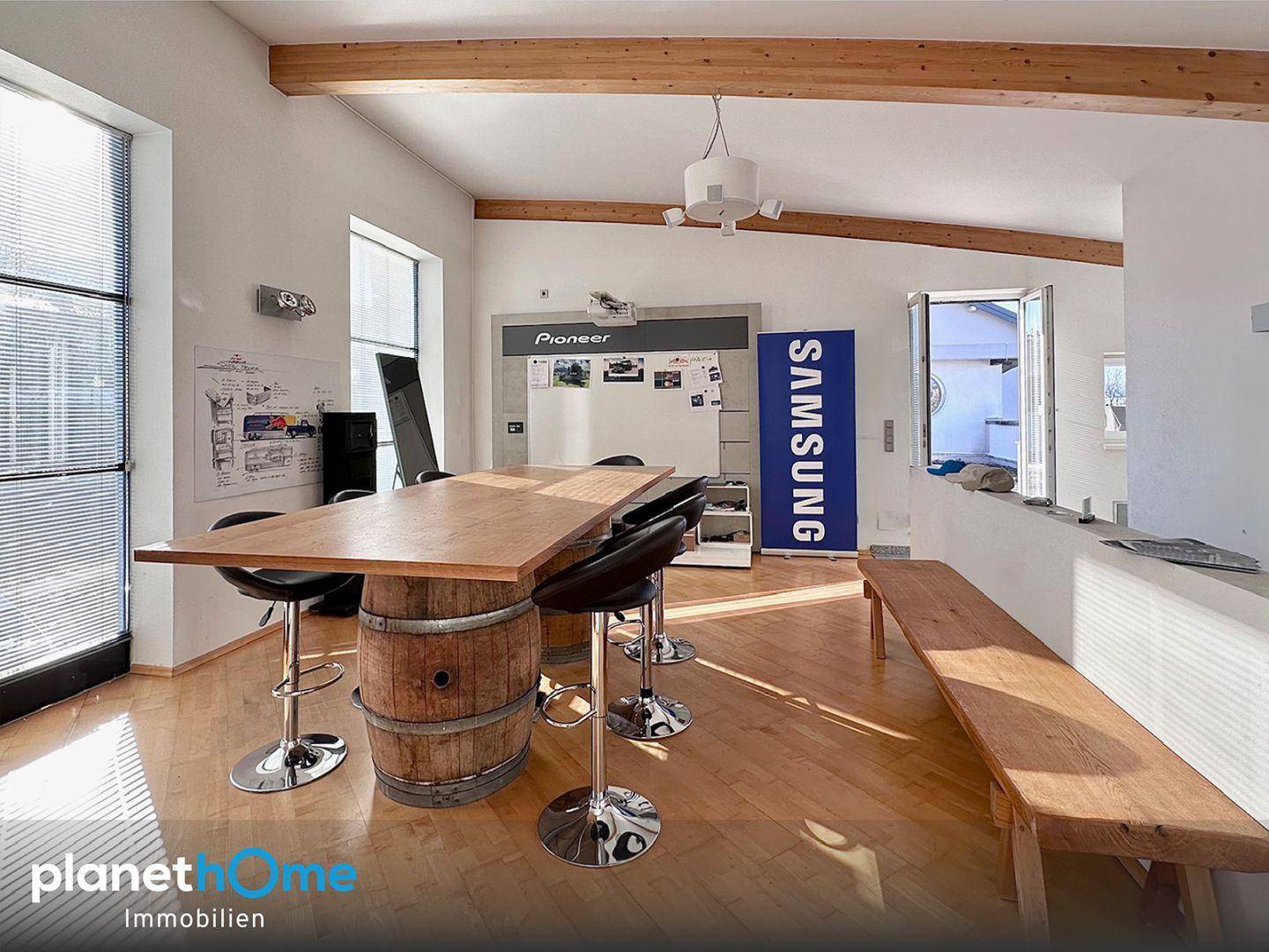Heller Lounge-Bereich mit Holzbalken, einem Bartisch und einer langen Holzbank, ideal für Pausen.