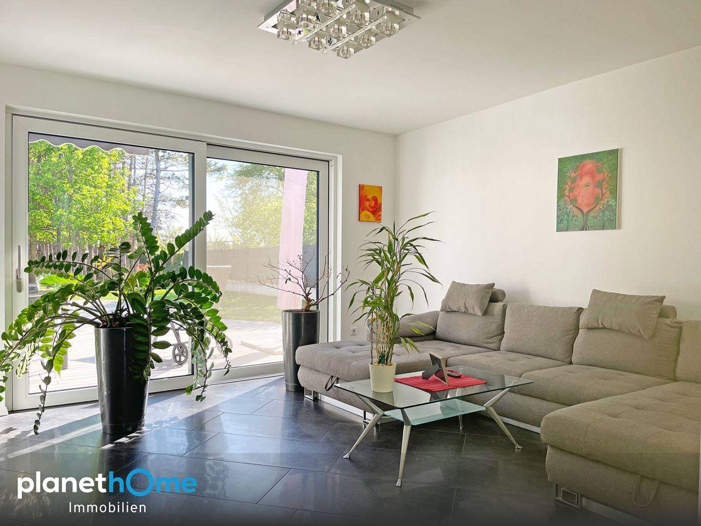 Lichtdurchflutetes Wohnzimmer mit großen Schiebetüren zum Garten und moderner Einrichtung.