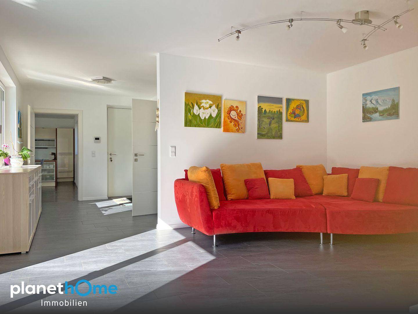 Geräumiges Wohnzimmer mit farbenfrohem Sofa und Blick in den angrenzenden Flur.