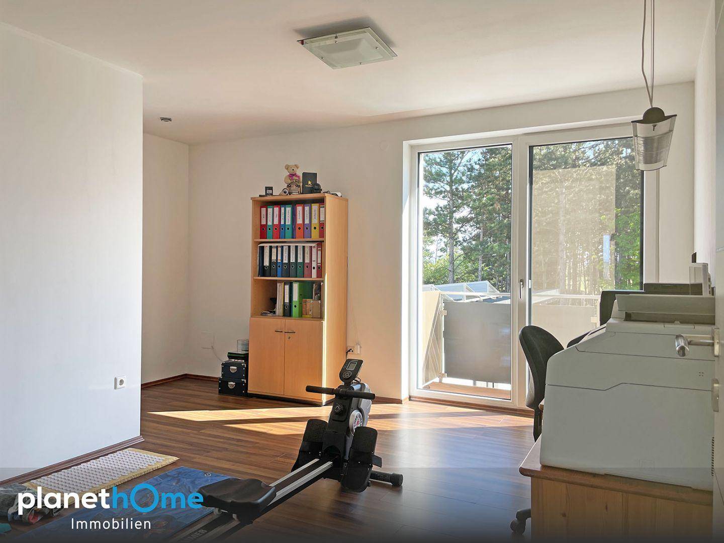 Vielseitiger Raum, genutzt als Büro und Fitnessbereich, mit Zugang zum Balkon.