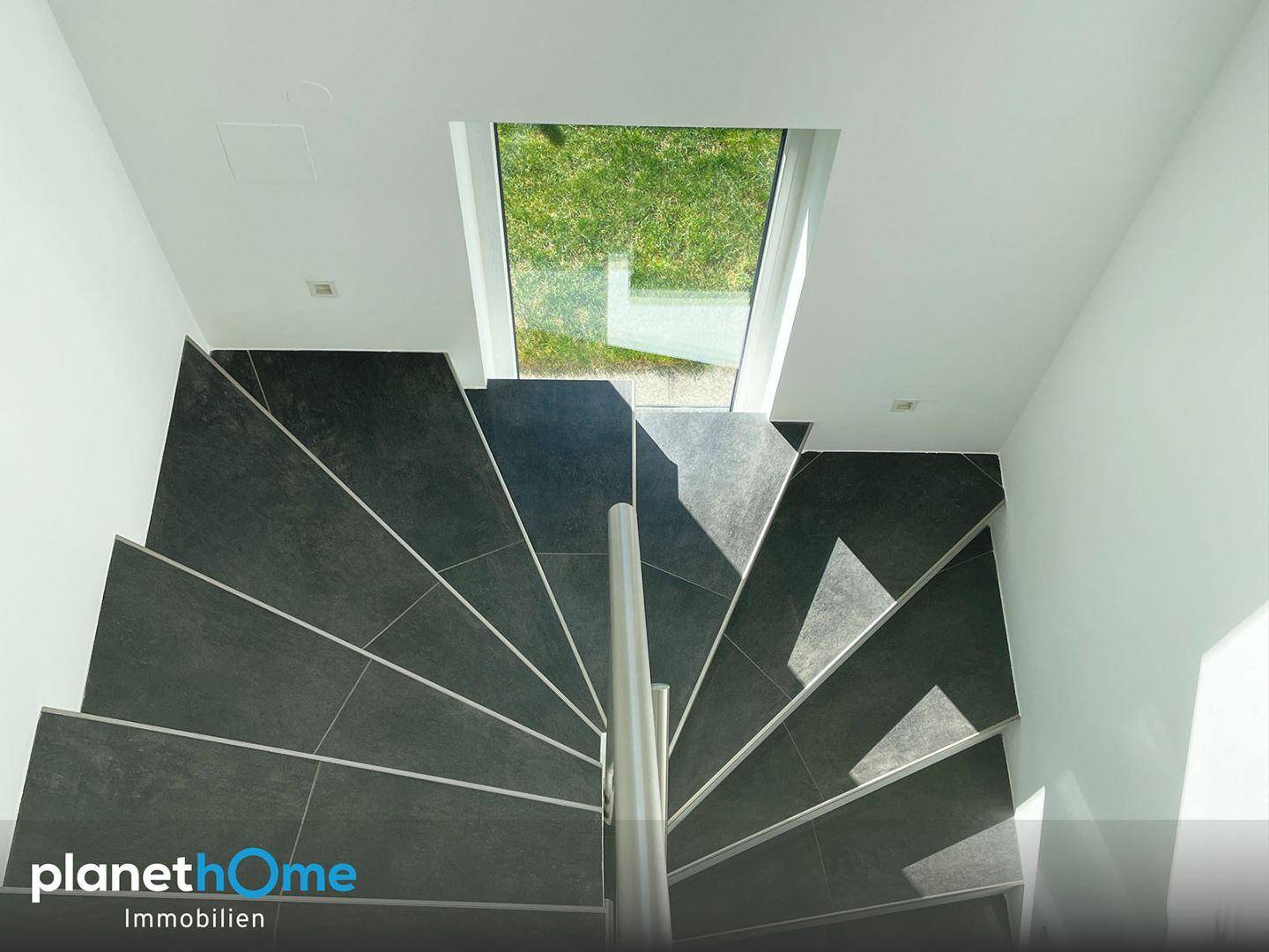 Moderne Treppe mit dunklen Fliesen und einem Oberlicht für natürliches Licht.