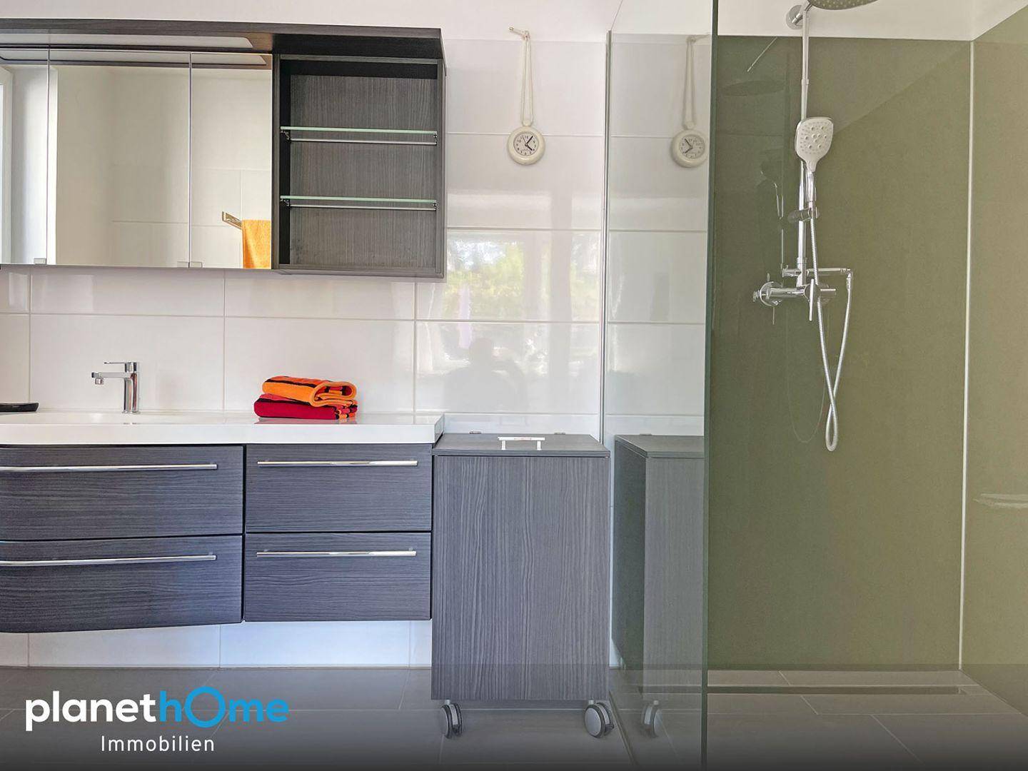 Modernes Badezimmer mit begehbarer Dusche, Waschtisch und Spiegelschrank.