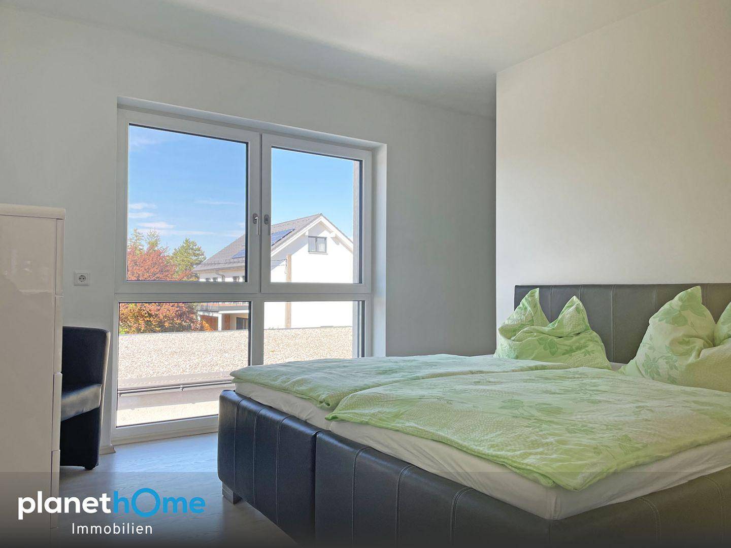 Helles Schlafzimmer mit großem Fenster und Blick auf die Umgebung.